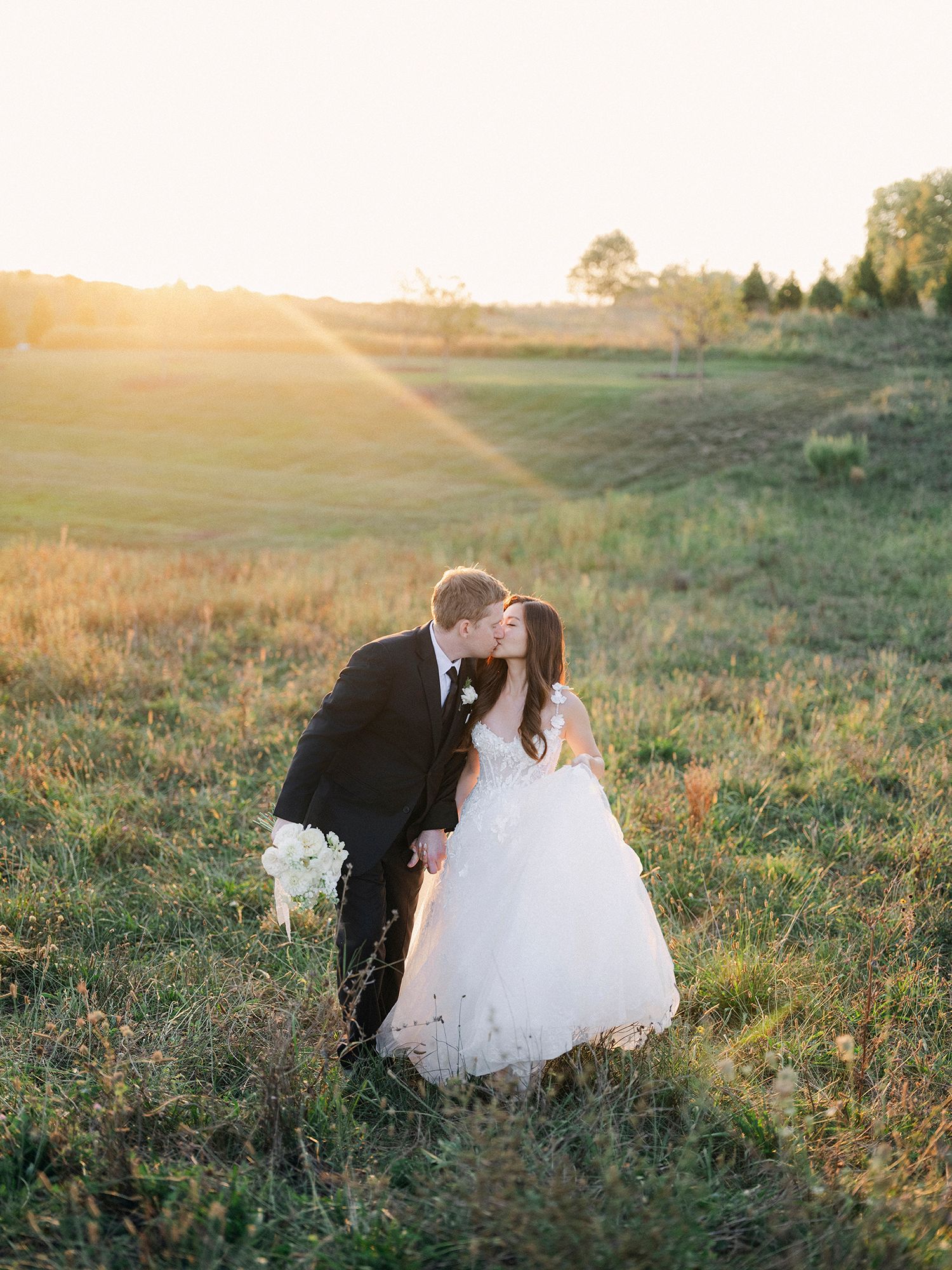 Wedding couple photographed in a sunlit meadow during golden hour. NYC wedding photographer.