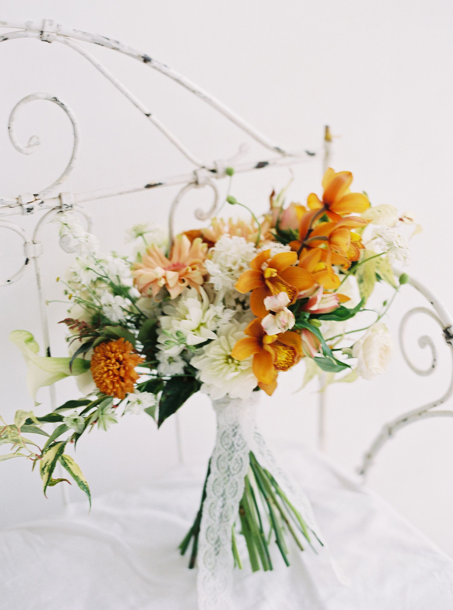 Delicate floral arrangement with orange lilies and white blooms on light background.