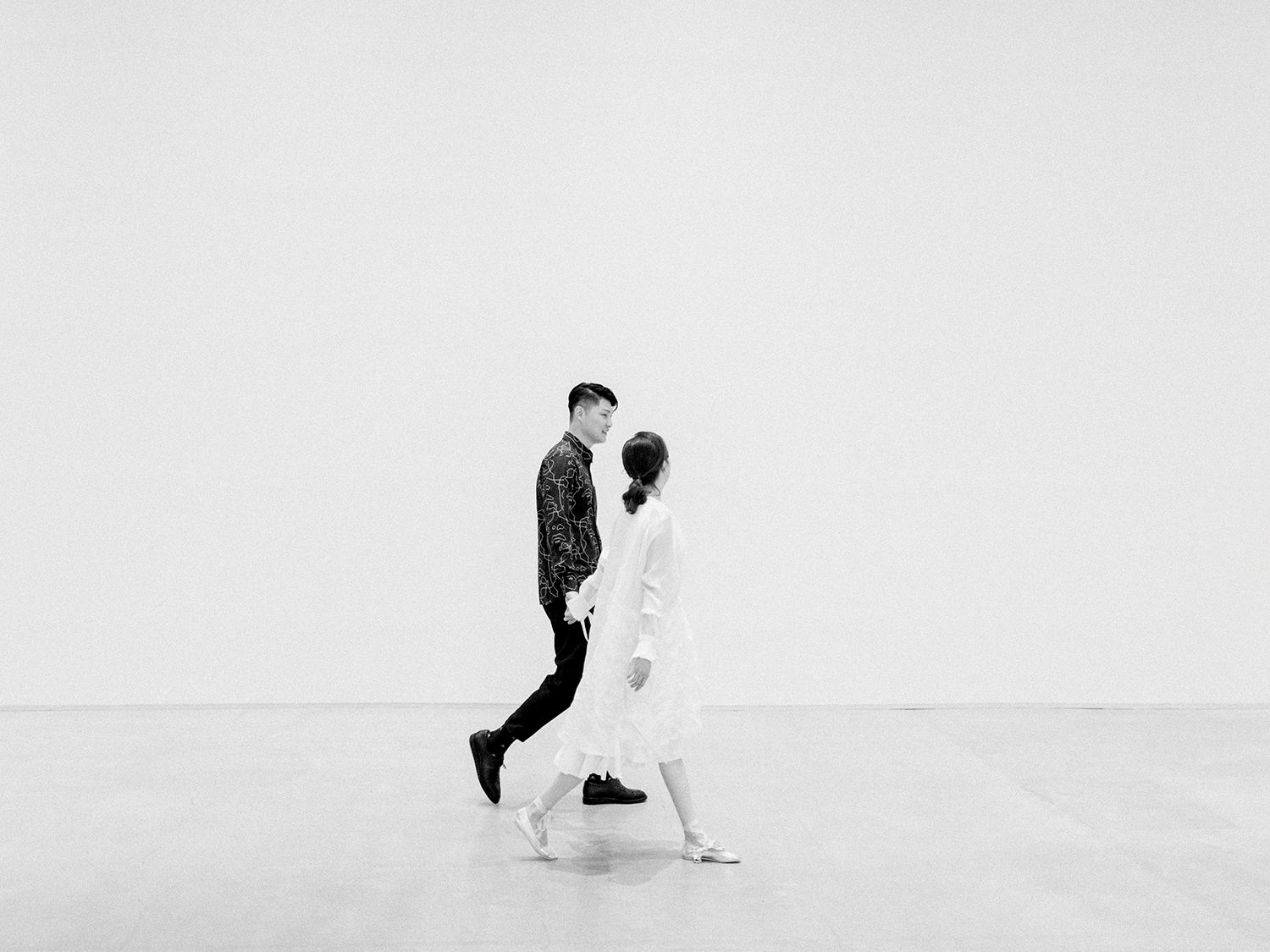 Artistic black and white engagement photos showing playful poses against white background.