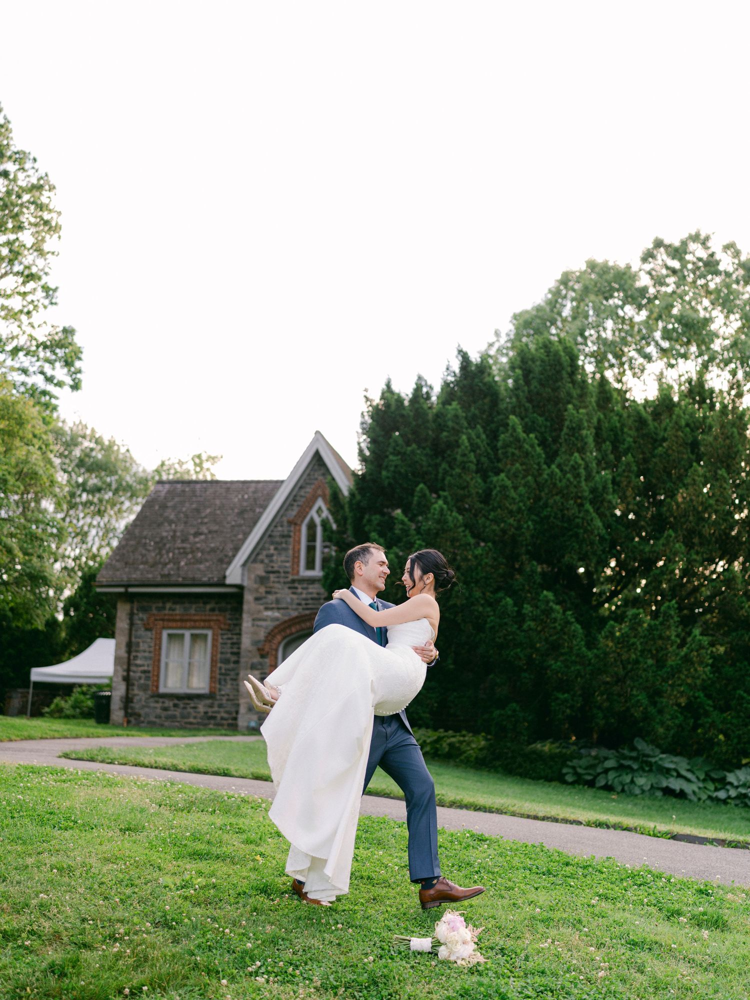 A celebratory lift moment on a grassy lawn with a stone cottage in the background.