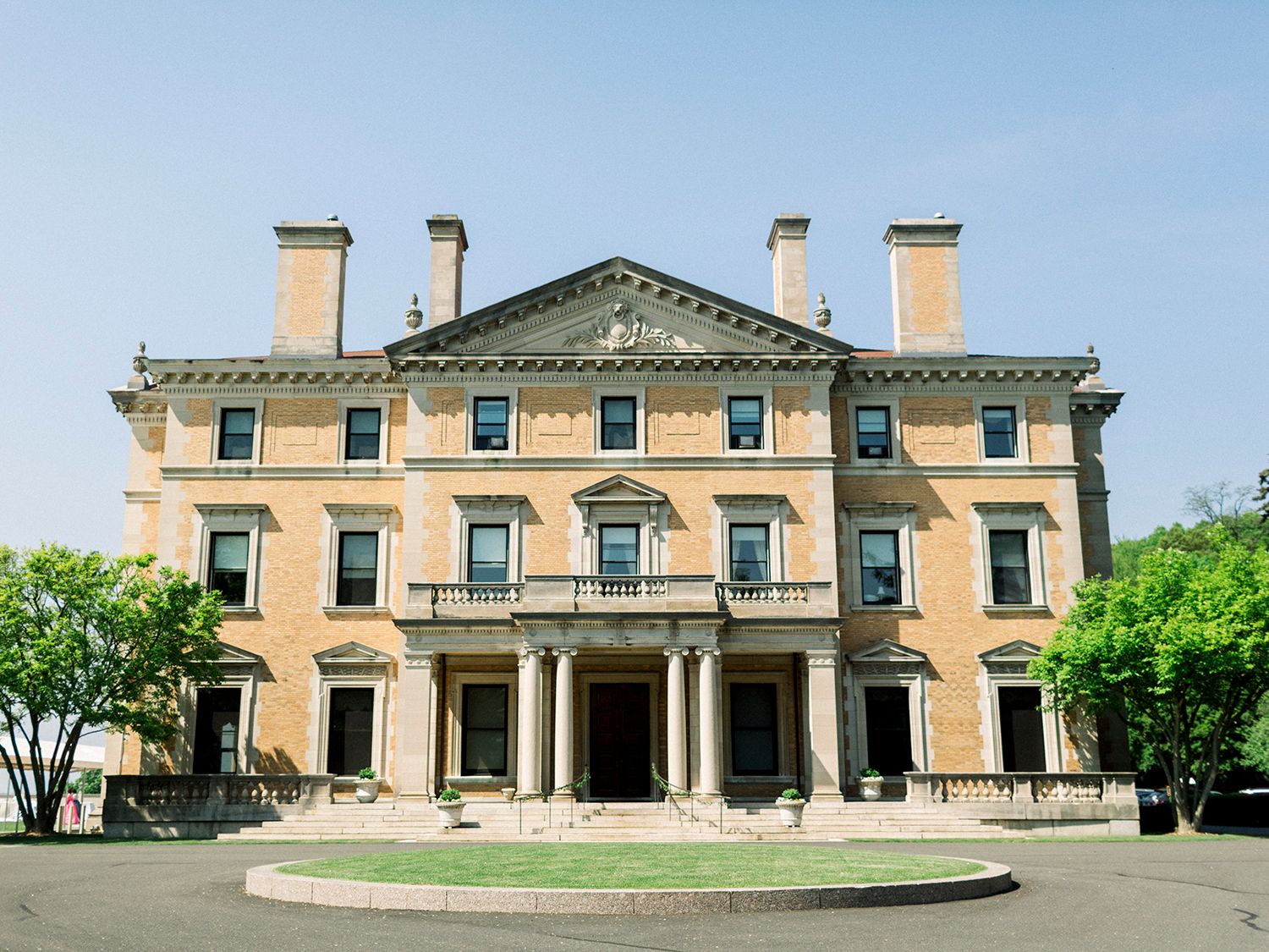 Stately historic mansion with neoclassical architecture and symmetrical design in warm beige stone.