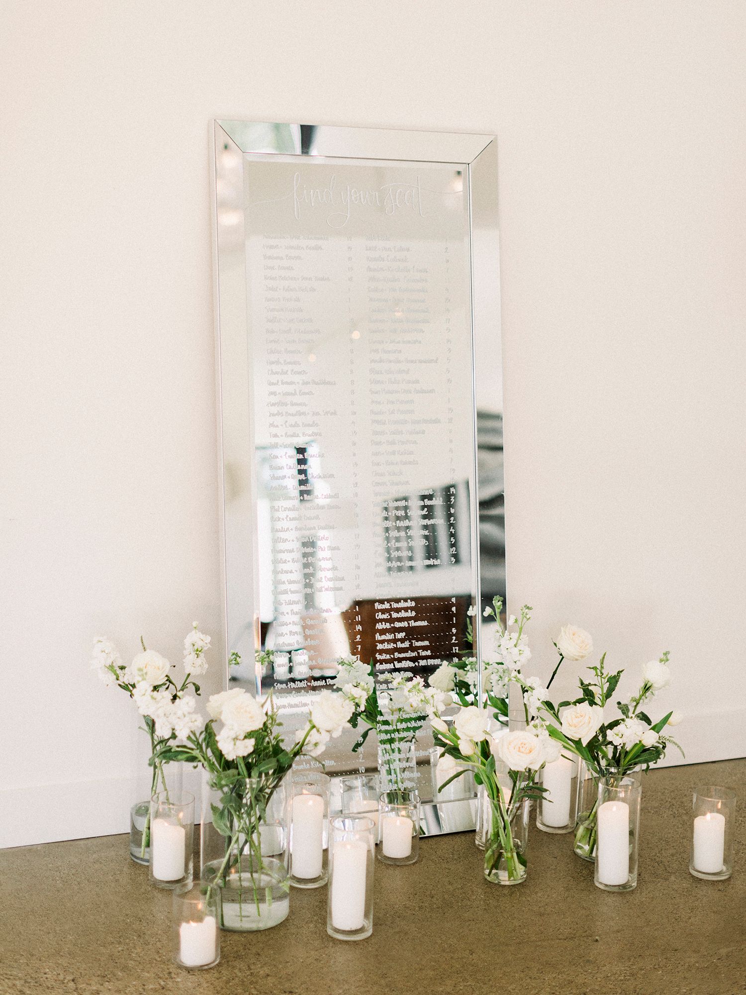 White candles and fresh flowers arranged in glass vases create an elegant wedding decor display.