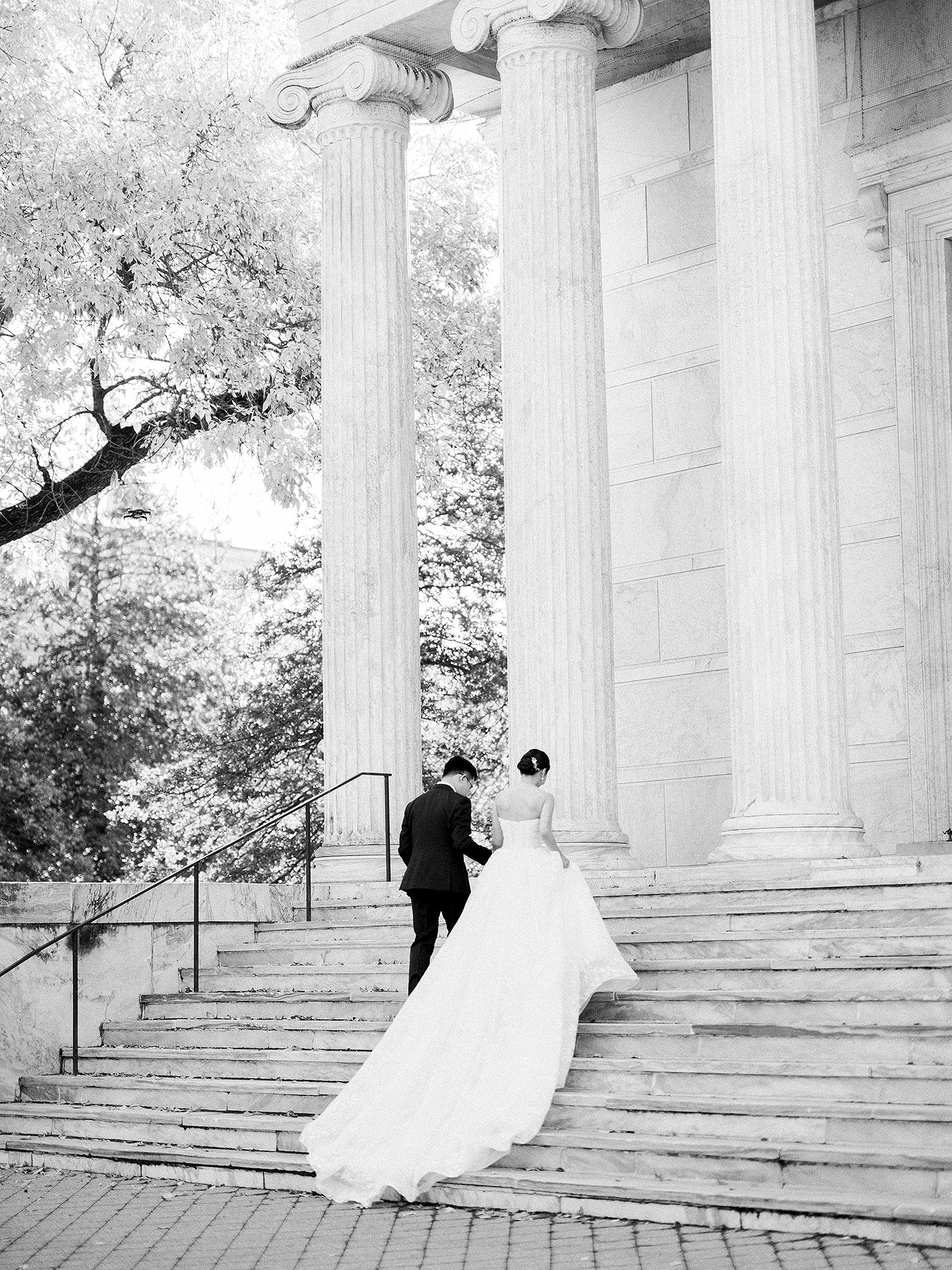 Elegant wedding photos on grand stone steps with classical columns in black and white. NYC wedding photographer.