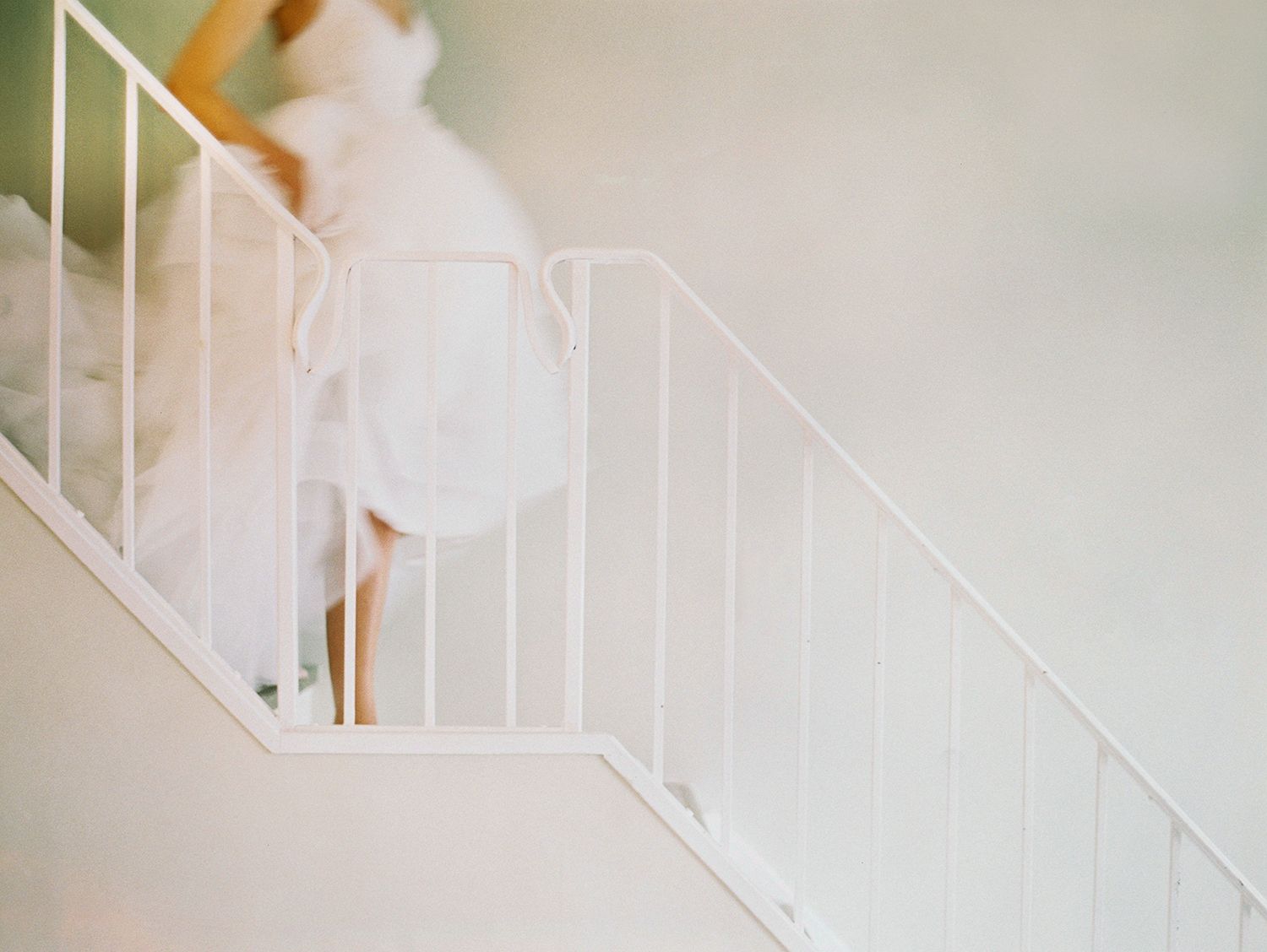 A white staircase with wrought iron railing against a light neutral background.