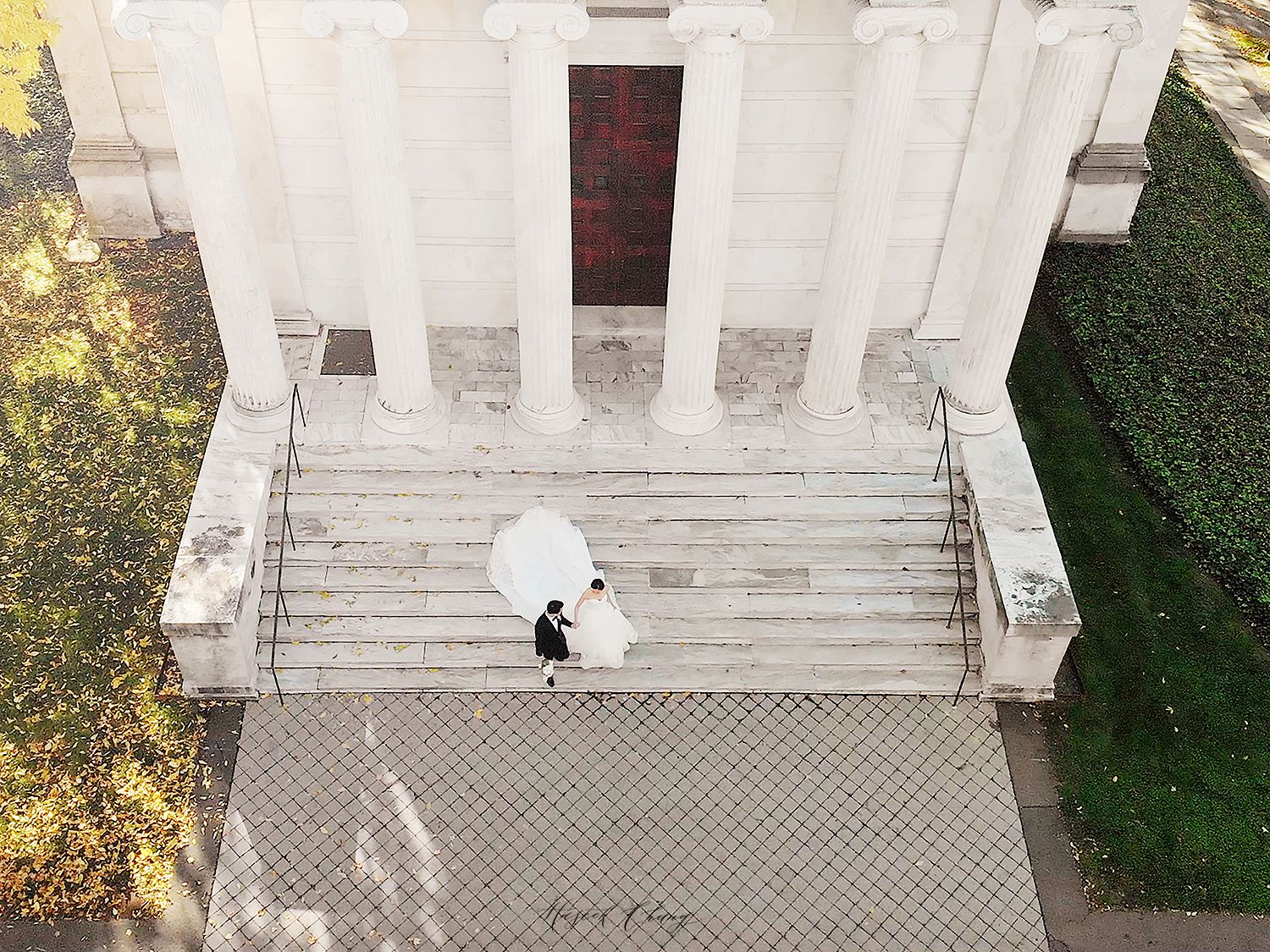 Architectural view of white stone building entrance with steps and columns. NYC wedding photographer.