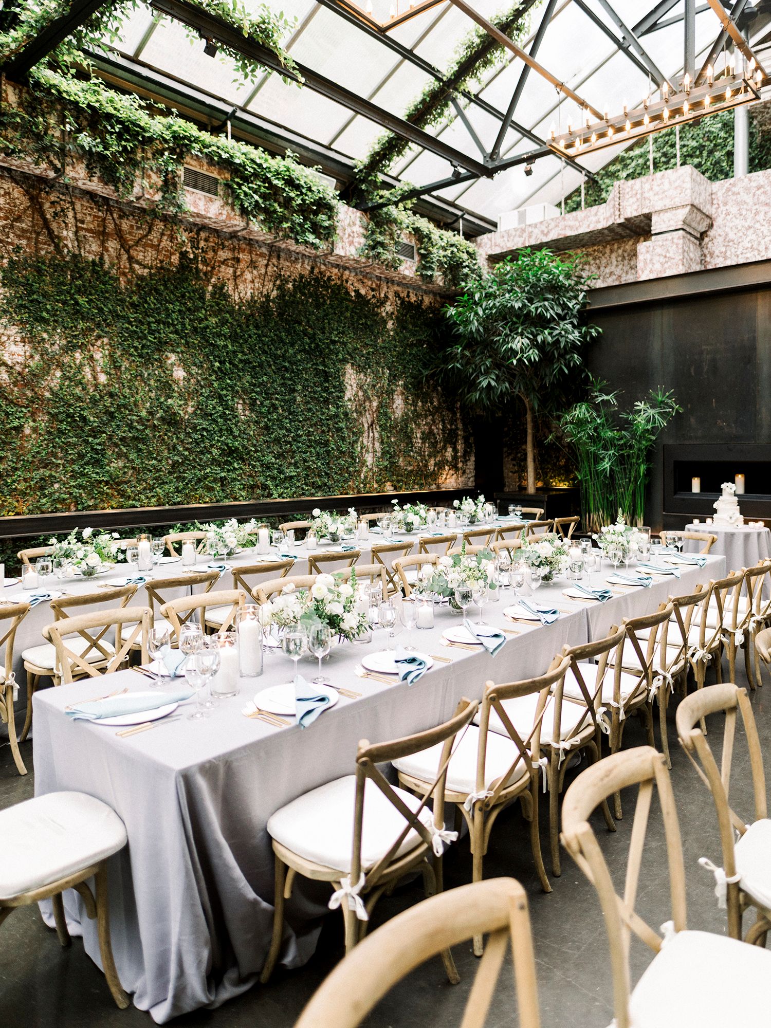 Industrial chic wedding reception venue with ivy-covered walls and long banquet tables. NYC wedding photographer.