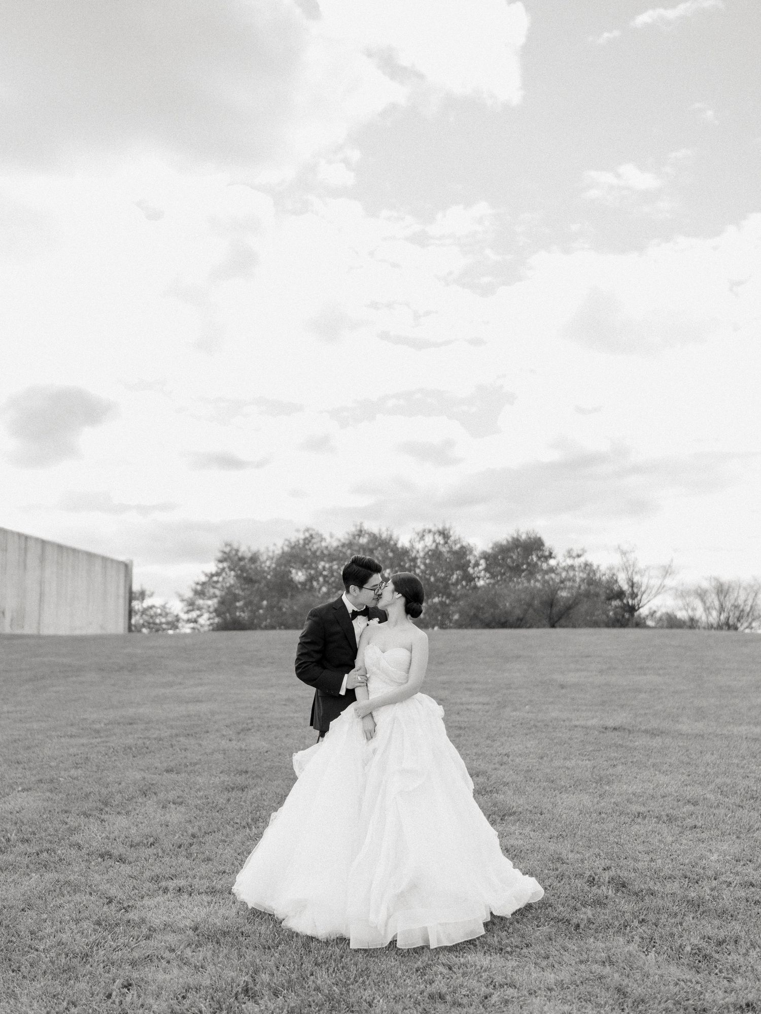 Wedding couple shares intimate moments in a sunlit meadow on their special day.