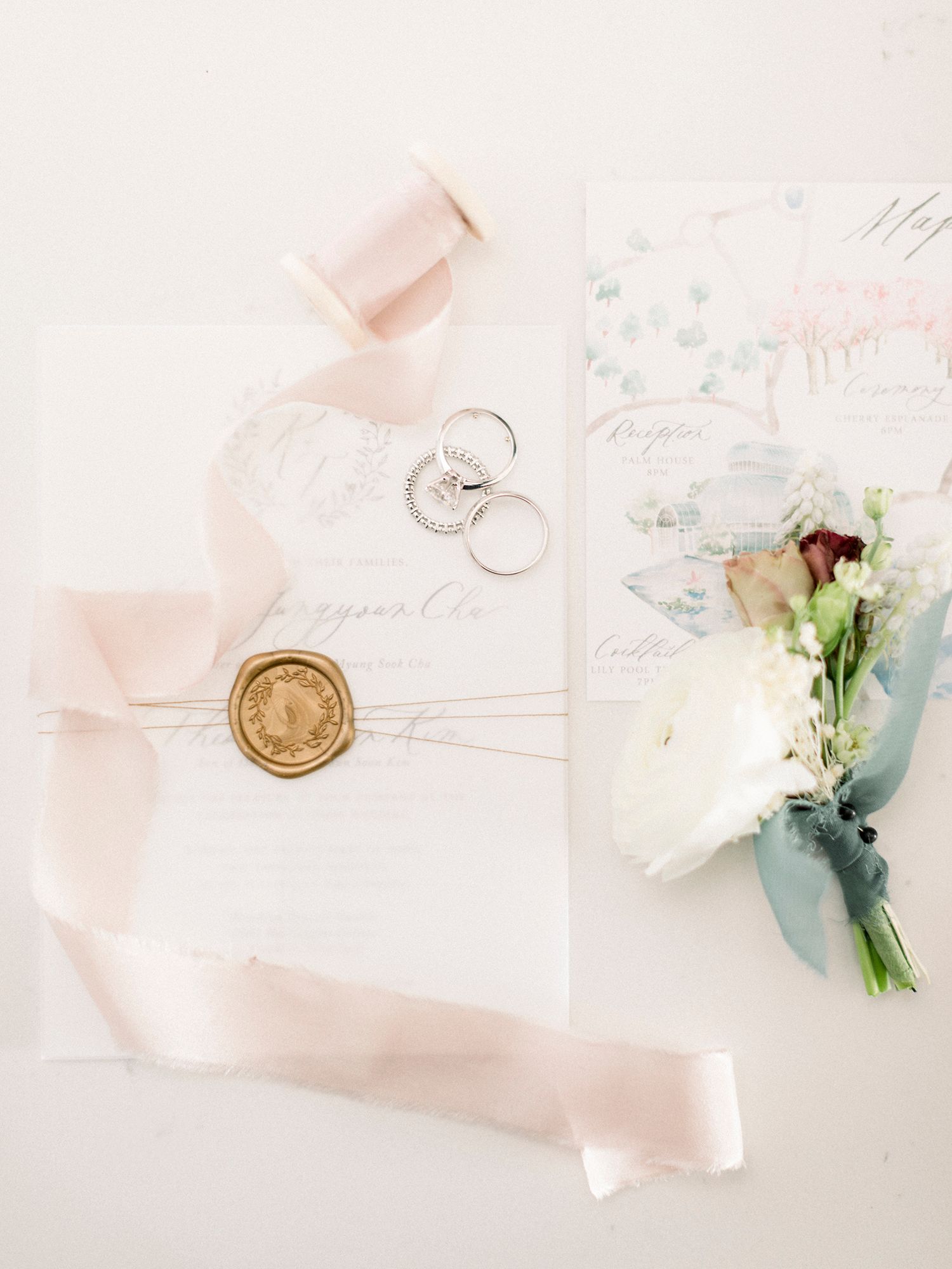 Wedding invitation suite with blush pink ribbon and floral details on white background.