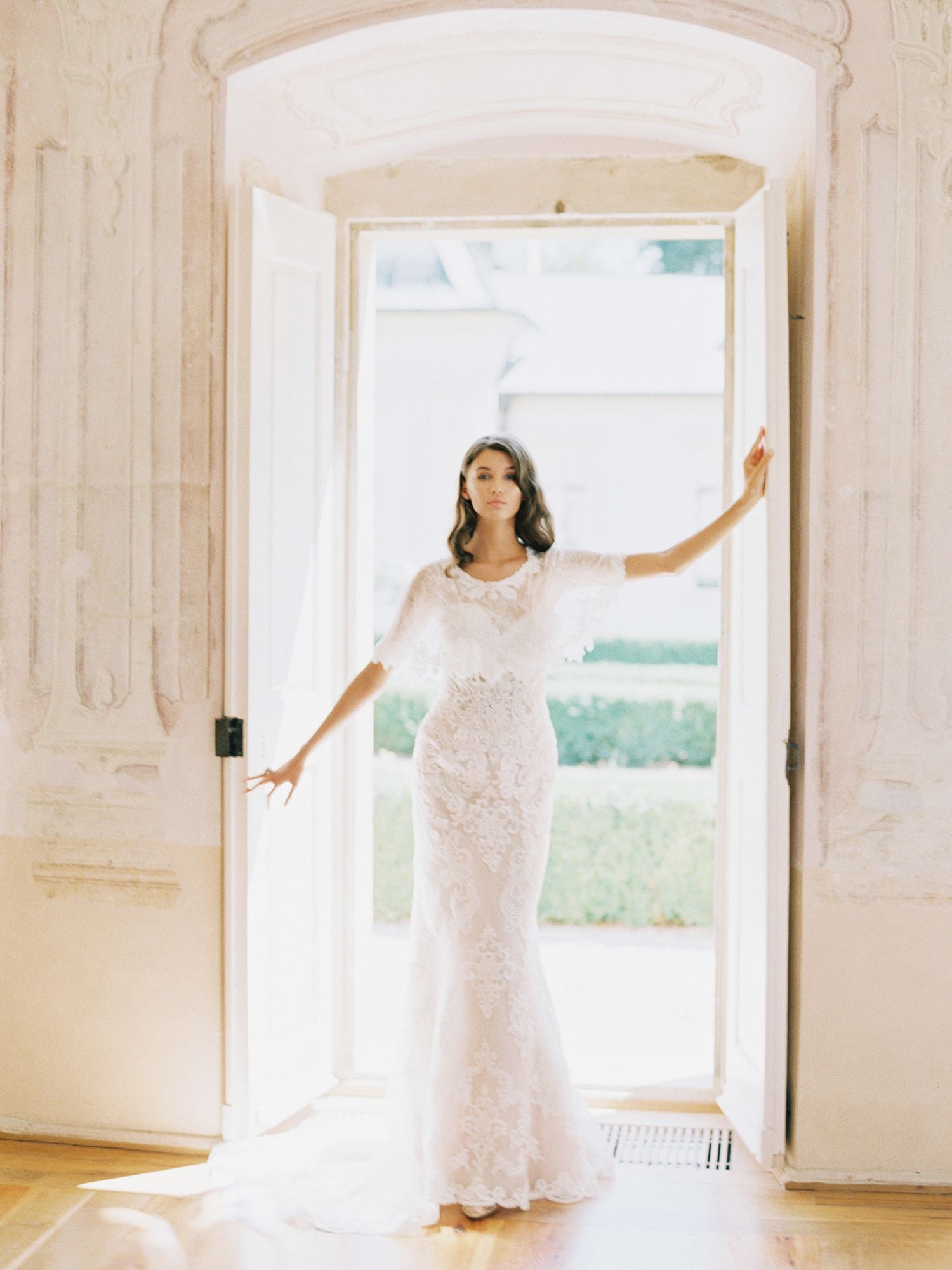 Ethereal white lace dress photographed in a sunlit room with architectural details.
