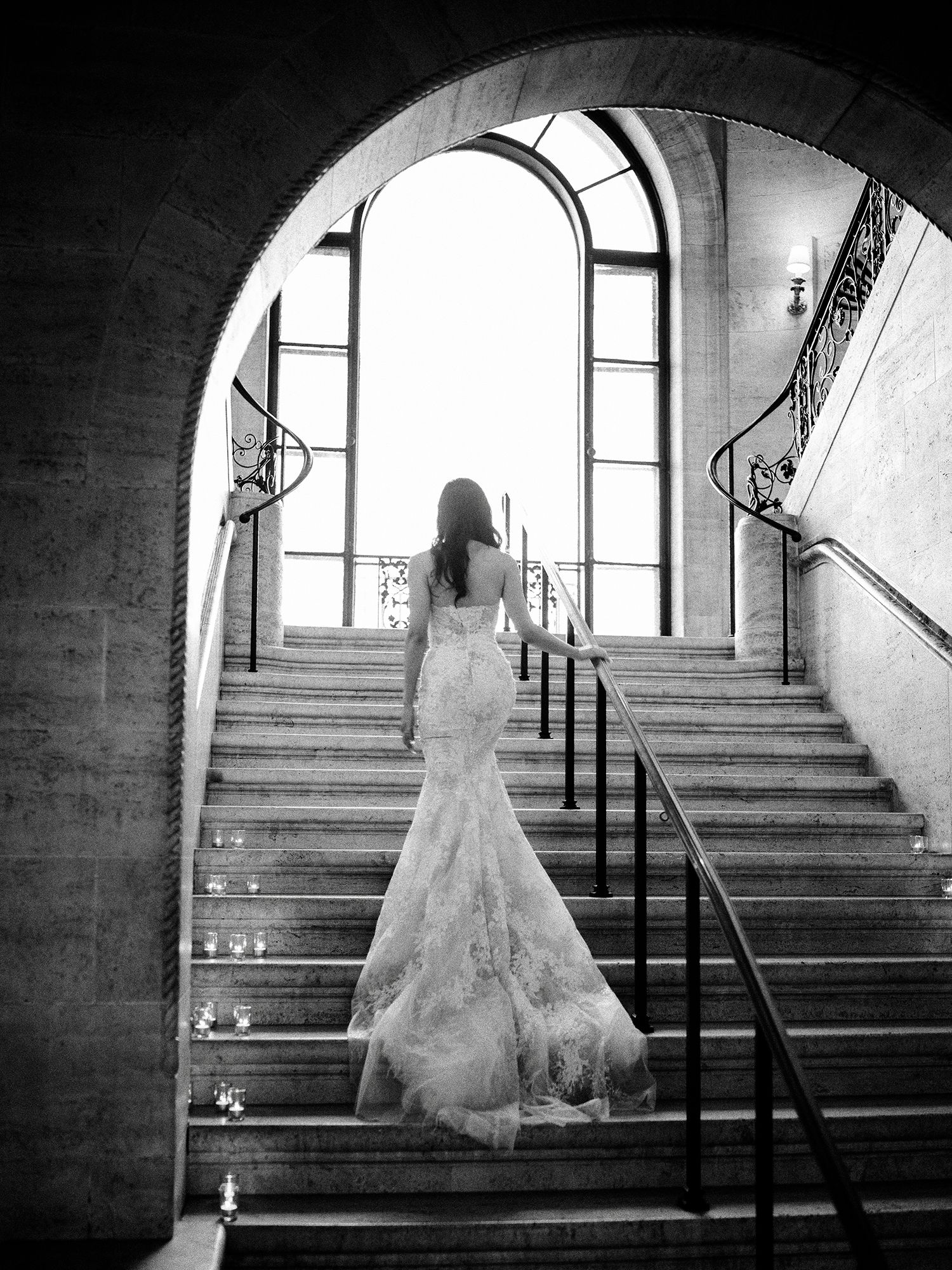 Dramatic black and white photos on stone steps with arched windows and natural light. NYC wedding photographer.