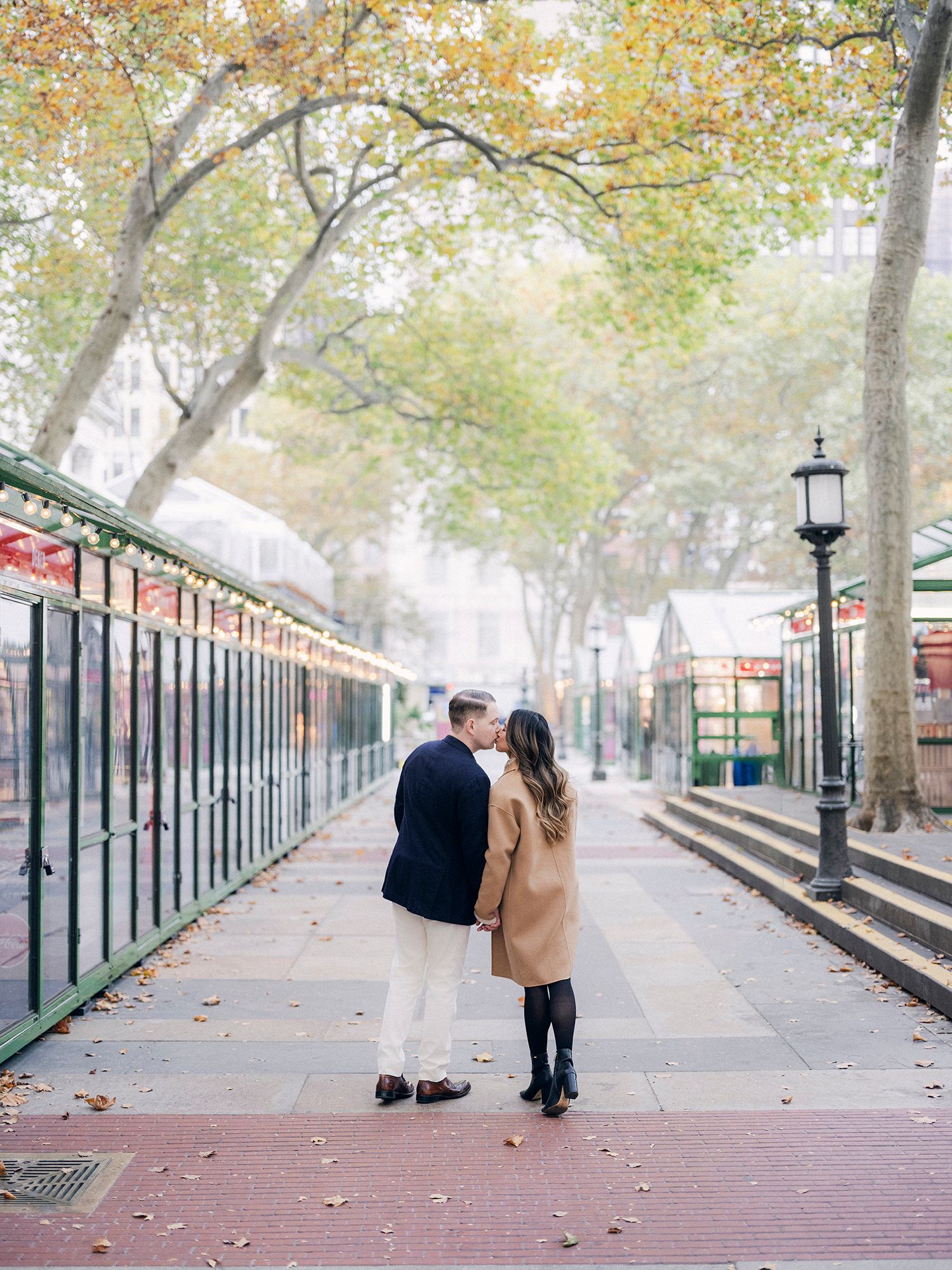 Couple walking along a tree-lined promenade in autumn.