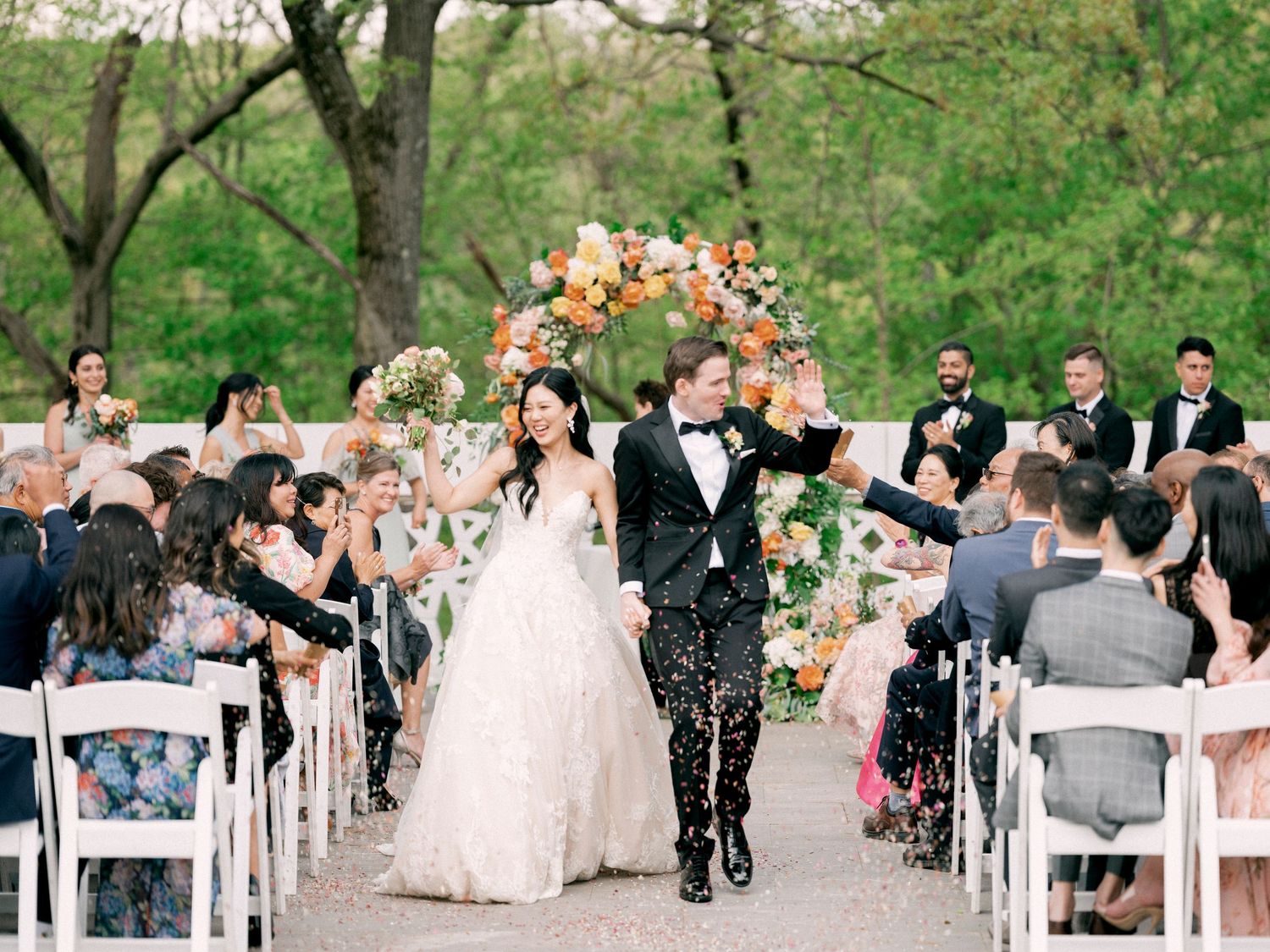 Outdoor garden wedding ceremony setup with white chairs and blooming trees in spring.