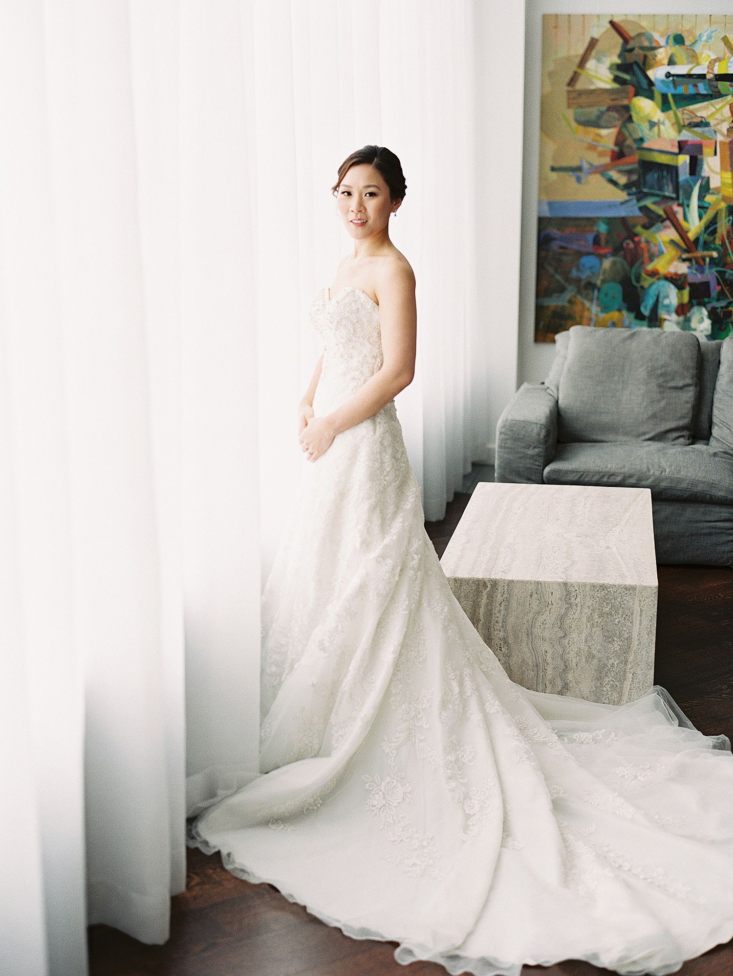 Bride in a flowing lace wedding gown poses in an elegant interior setting. NYC wedding photographer.
