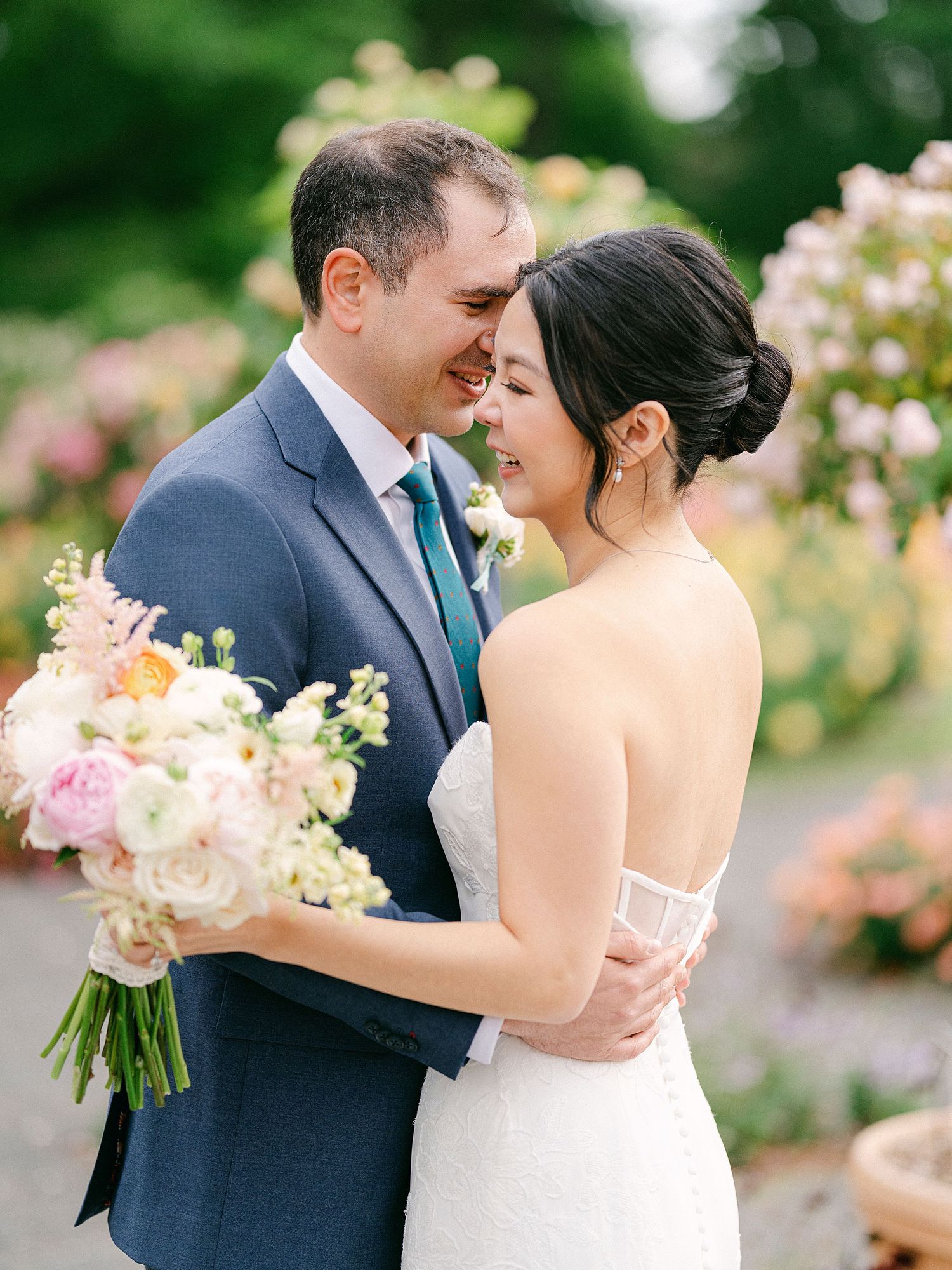 Romantic wedding portraits in a blooming rose garden with soft natural lighting. NYC wedding photographer.
