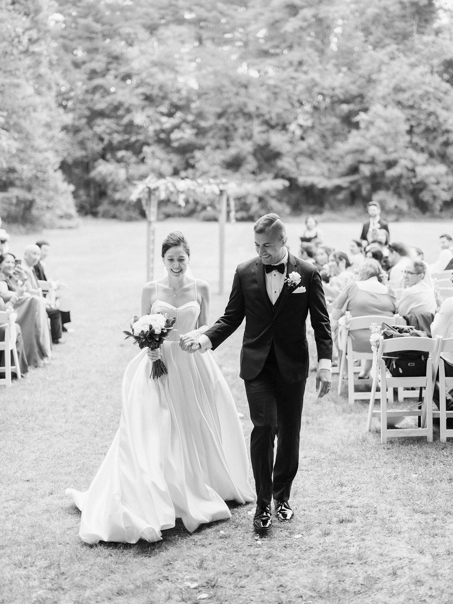 Black and white photo of a wedding ceremony setup with white chairs on an outdoor lawn. NYC wedding photographer.