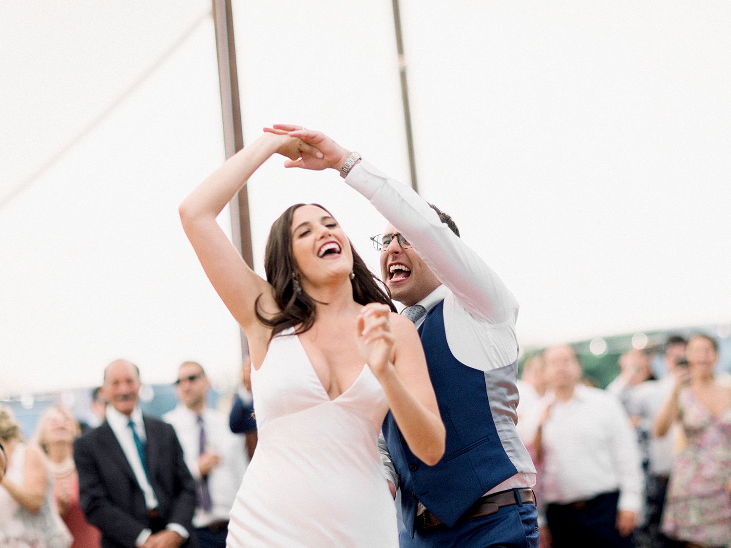 A couple dances together during their wedding celebration in a tented venue.