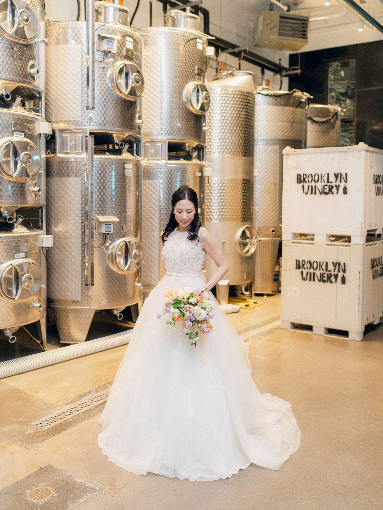 Wedding photography session in a modern winery with stainless steel fermentation tanks.
