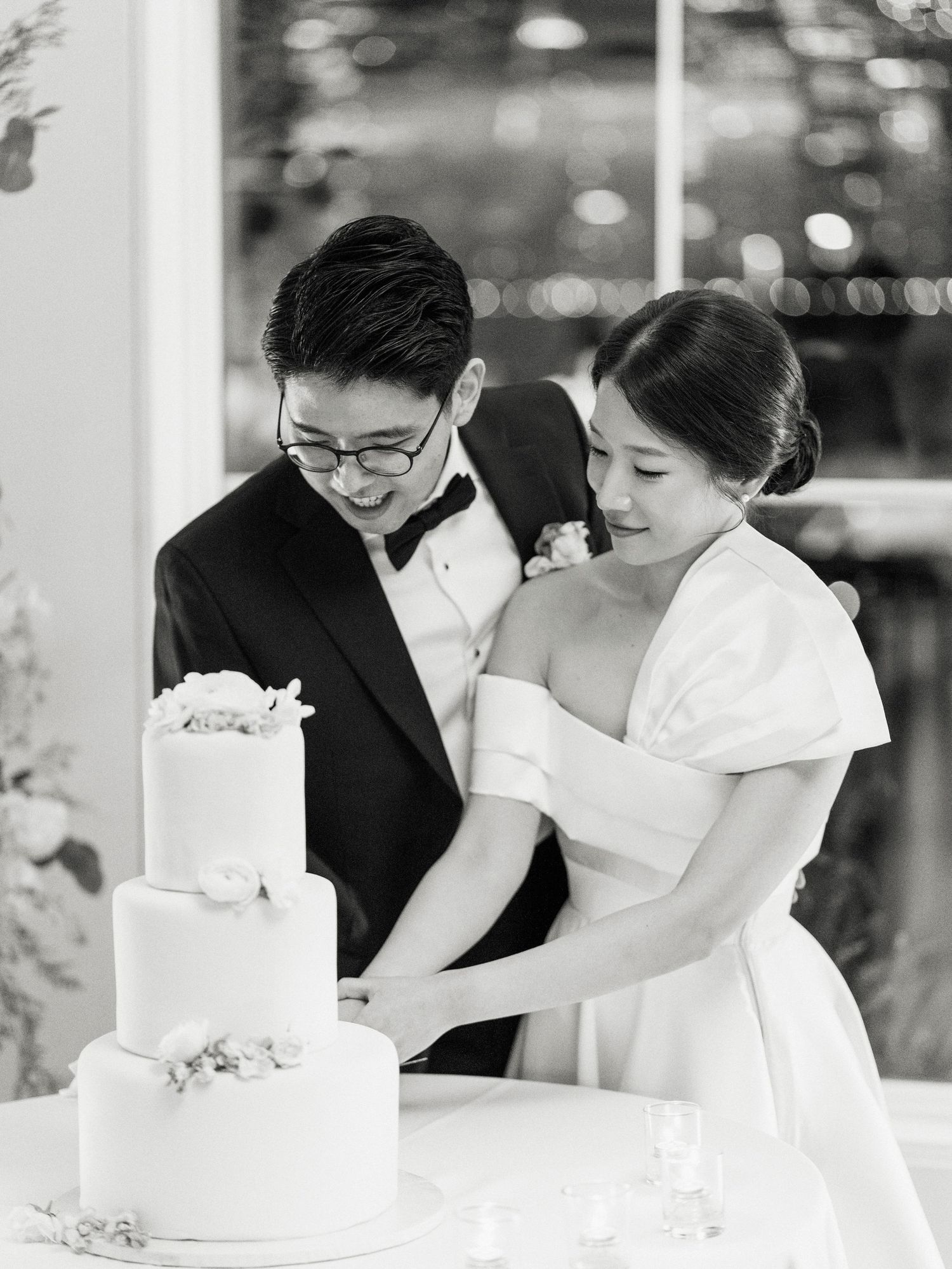 A couple cuts their elegant white wedding cake together during their reception celebration.