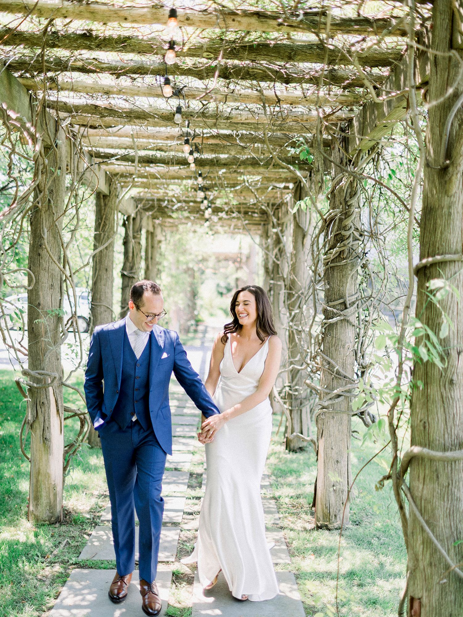 Couple sharing a joyful moment under a vine-covered garden pergola.