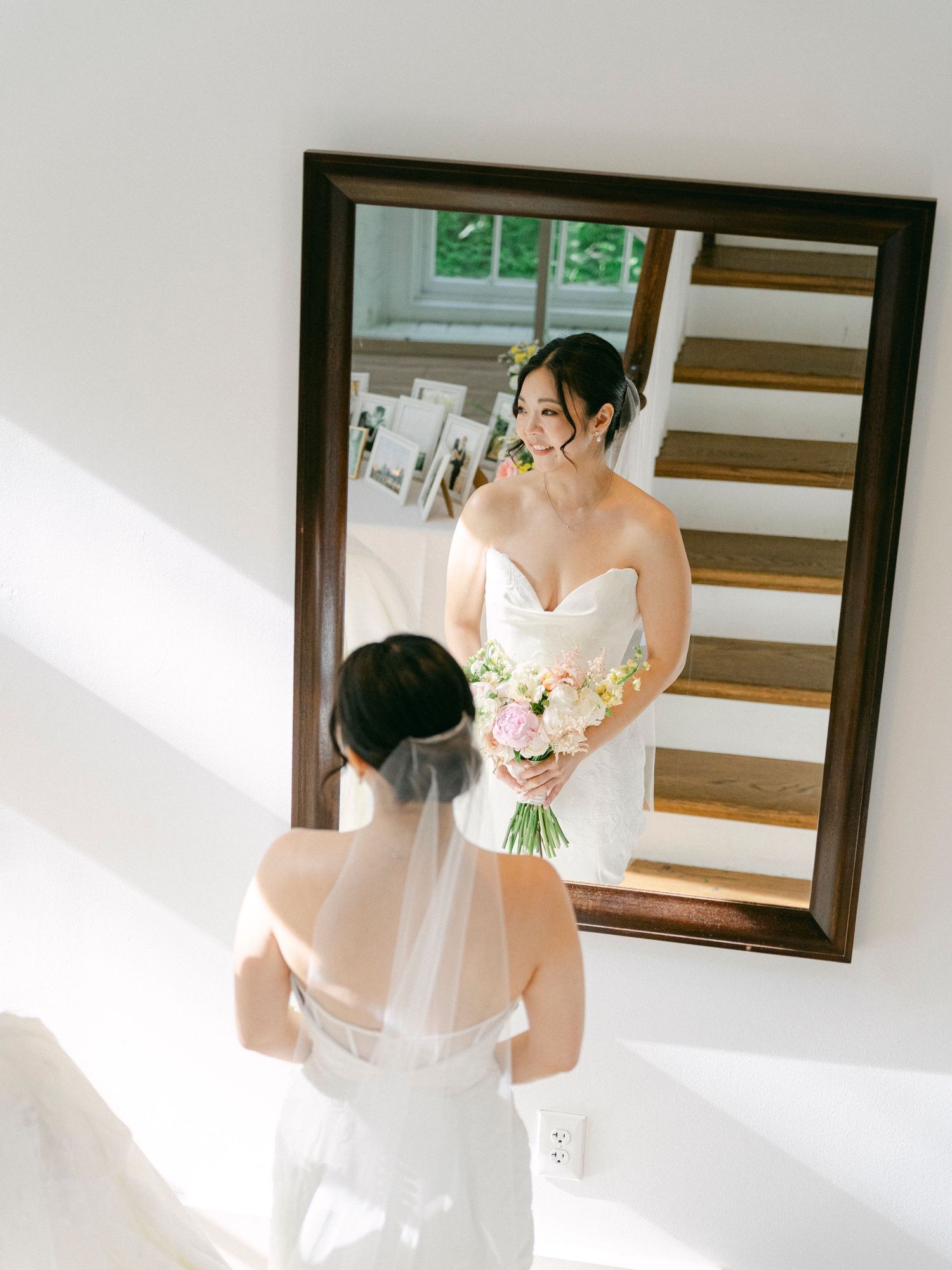 A reflection in a mirror shows a white wedding dress and delicate bouquet.