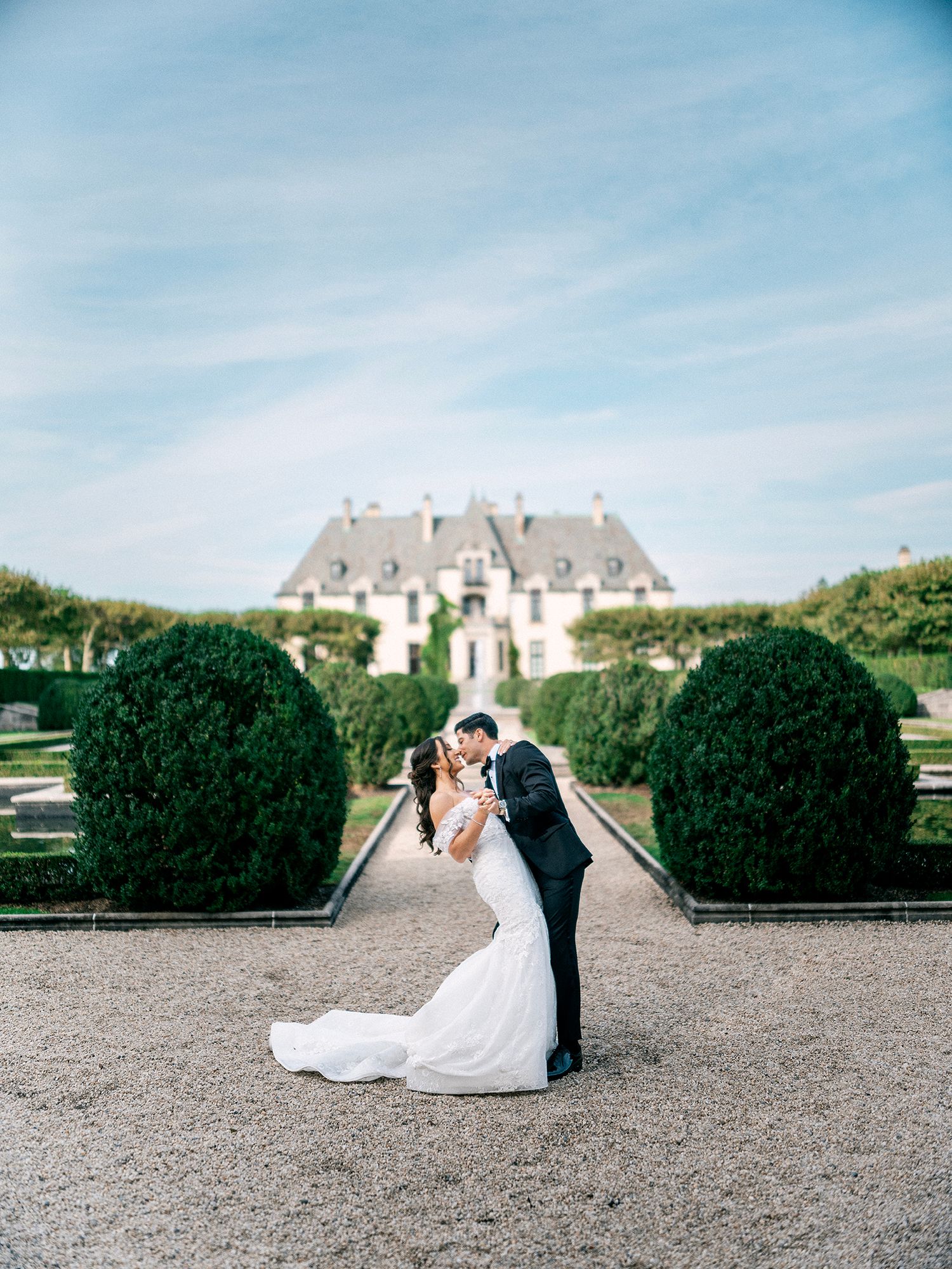 Romantic wedding portrait in front of a grand estate with manicured gardens and topiary. Oheka castle, NYC wedding photographer.