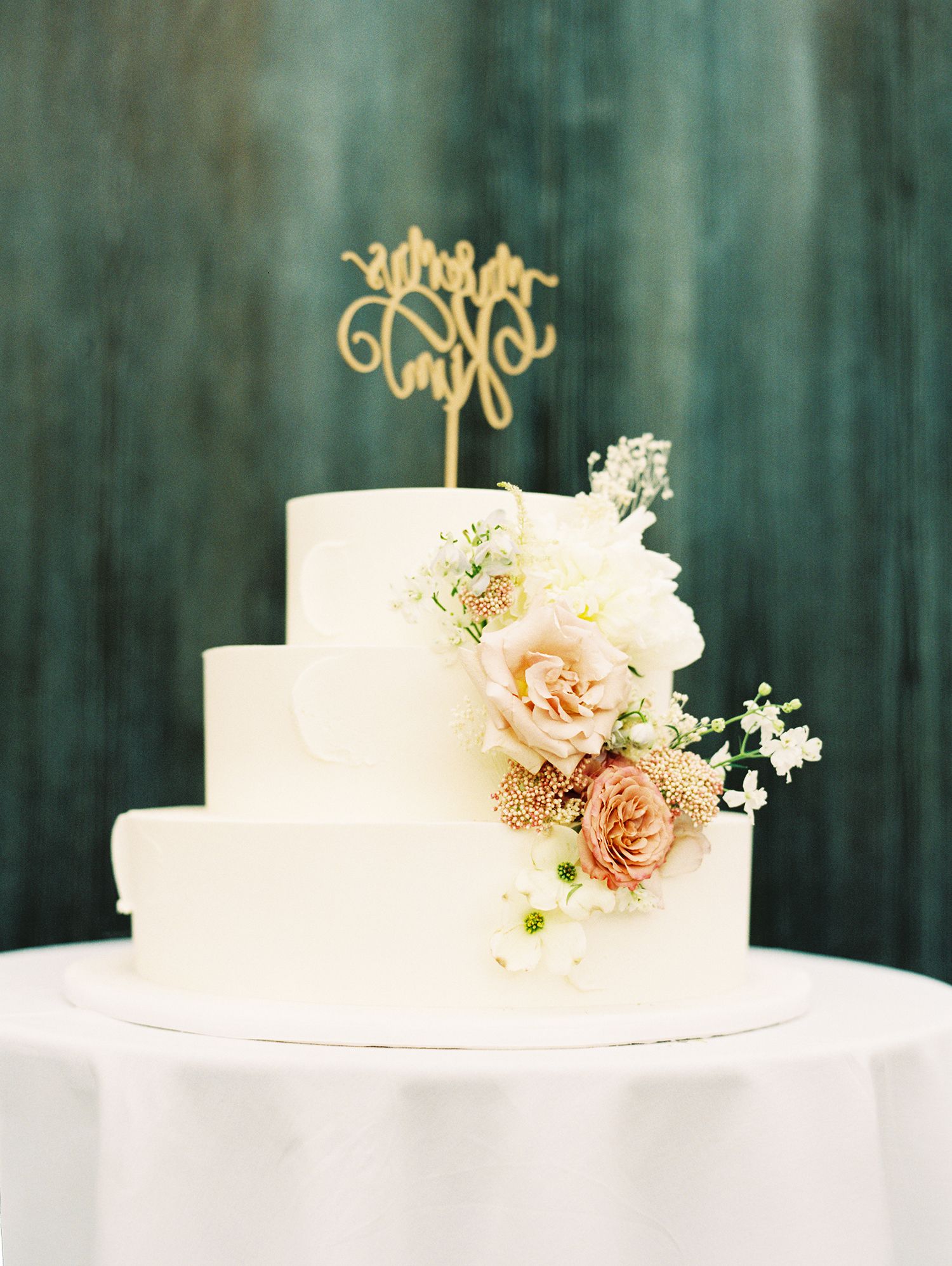 Elegant white wedding cake decorated with fresh peach roses and delicate flowers.