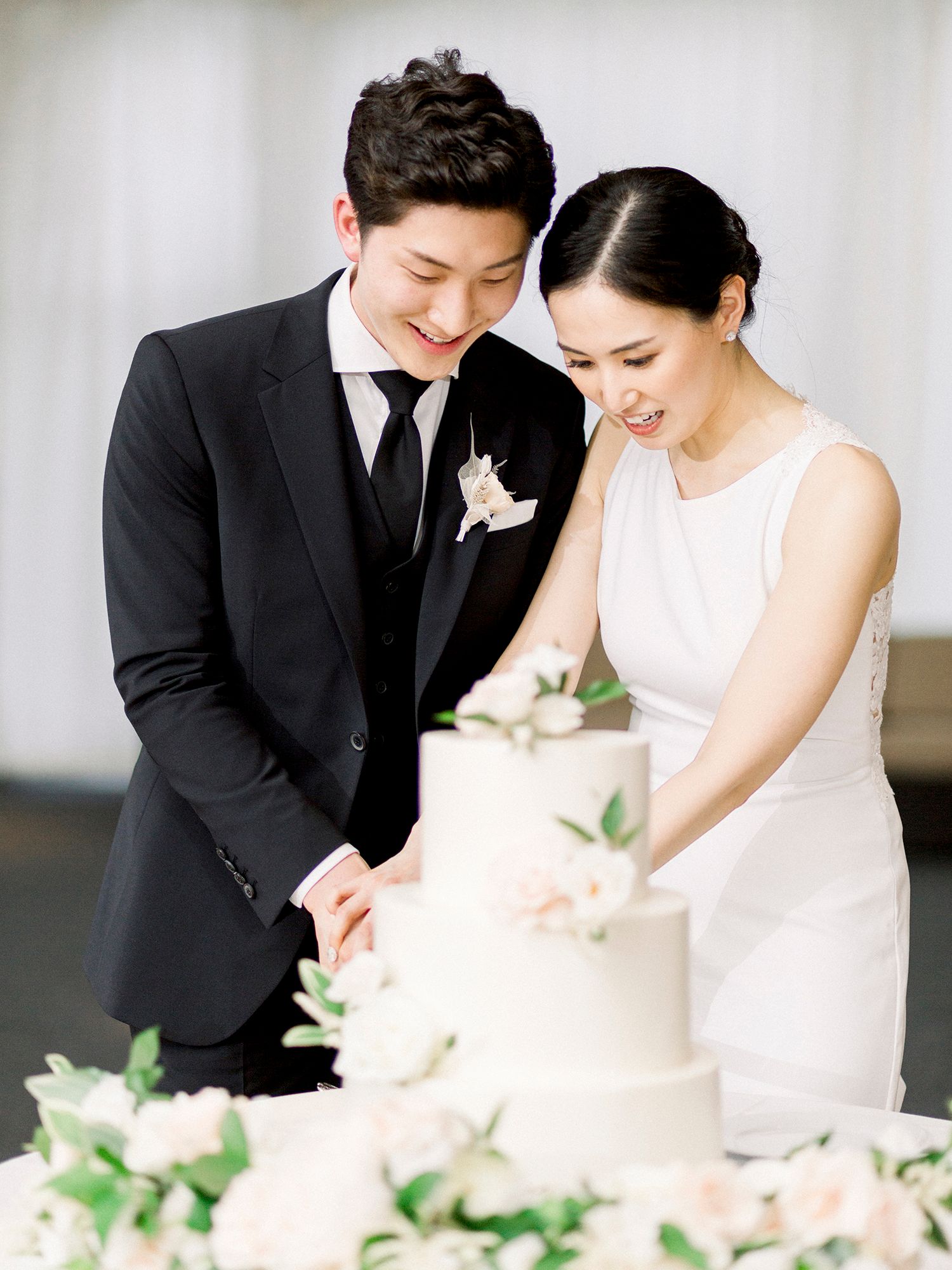 Wedding couple sharing sweet moments while cutting their elegant white cake.