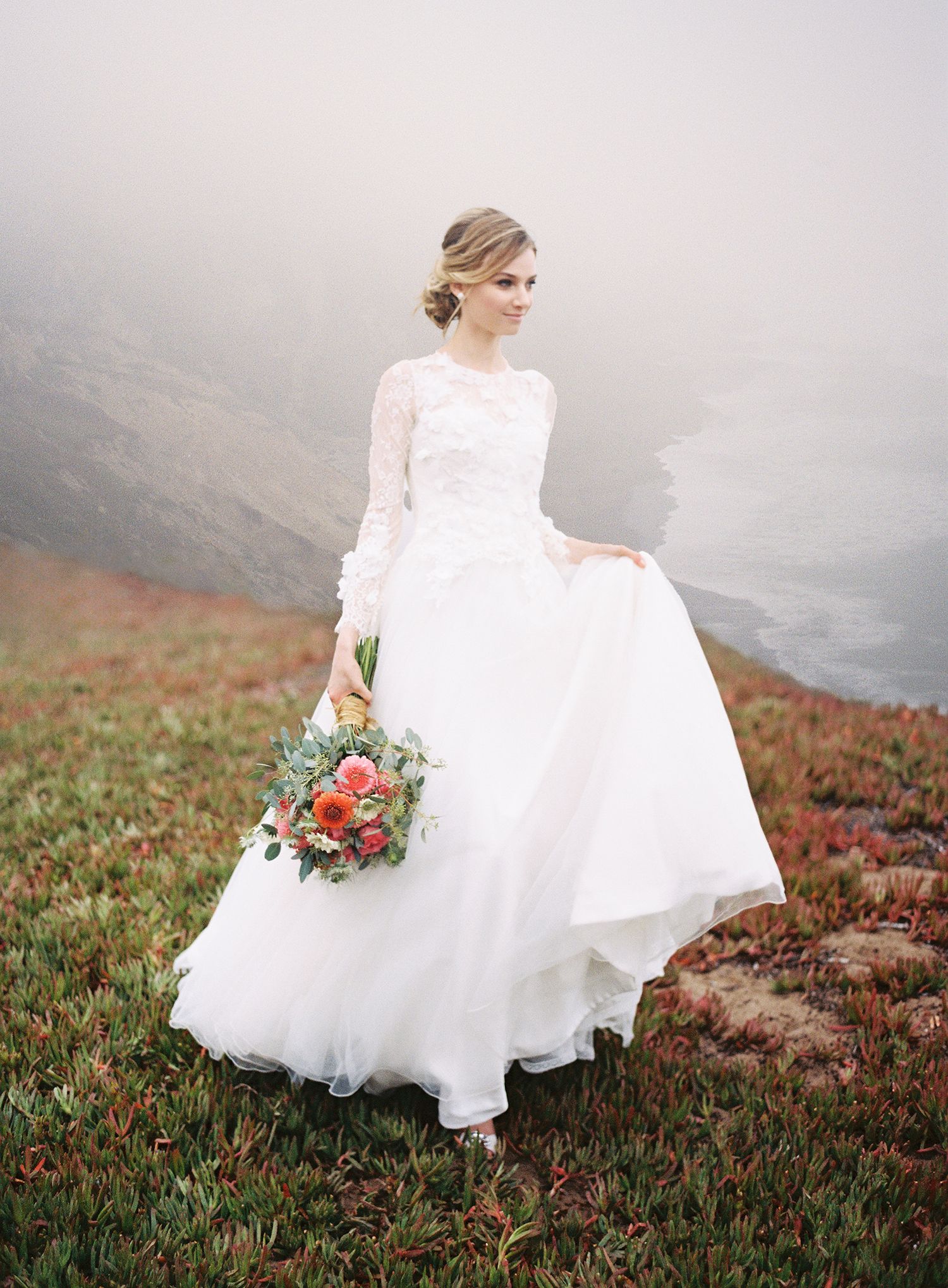 A white wedding dress billows in the wind against a misty mountainous landscape. NYC wedding photographer.