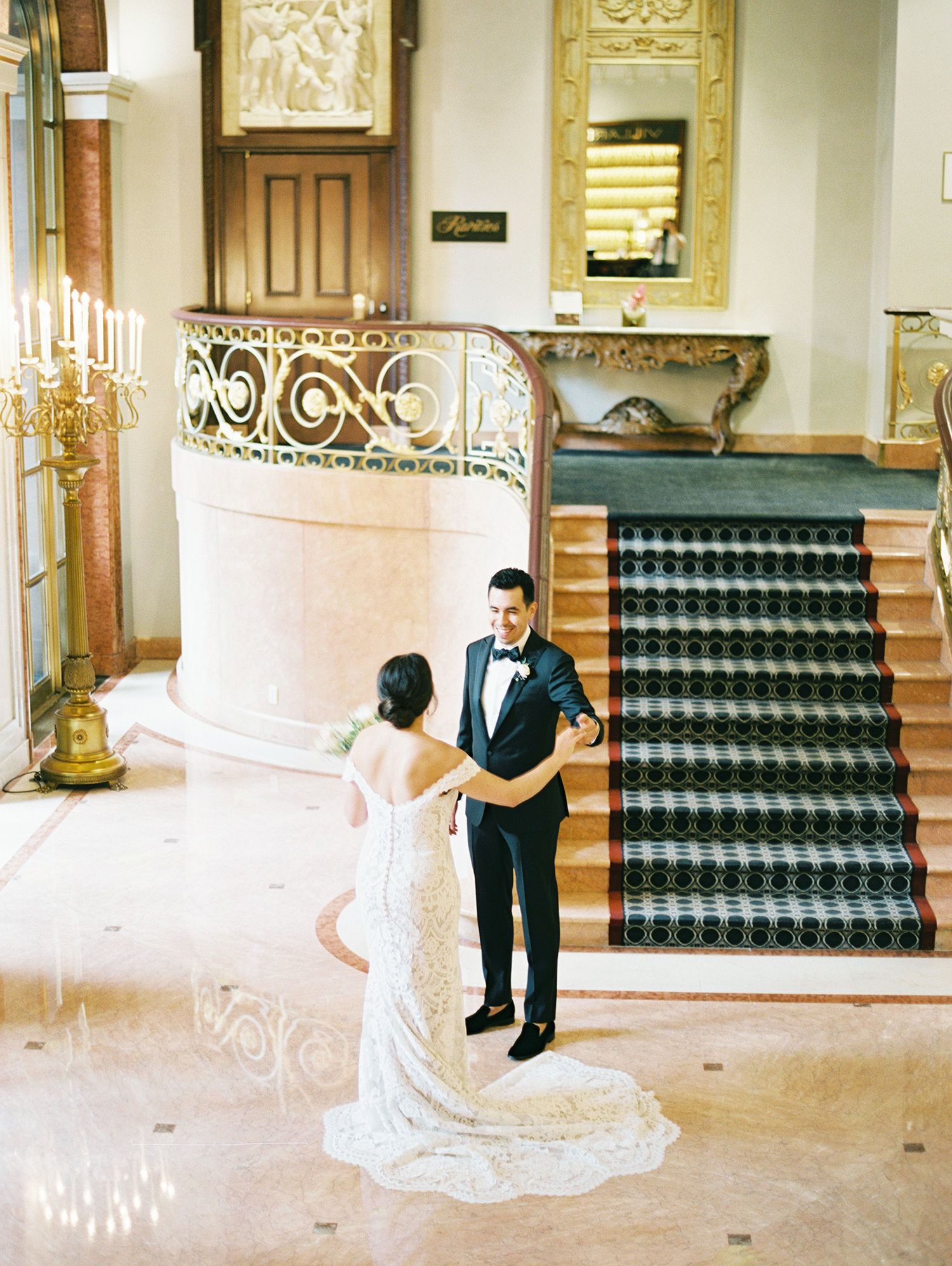Elegant wedding moment captured on ornate staircase with decorative iron railing. NYC wedding photographer.