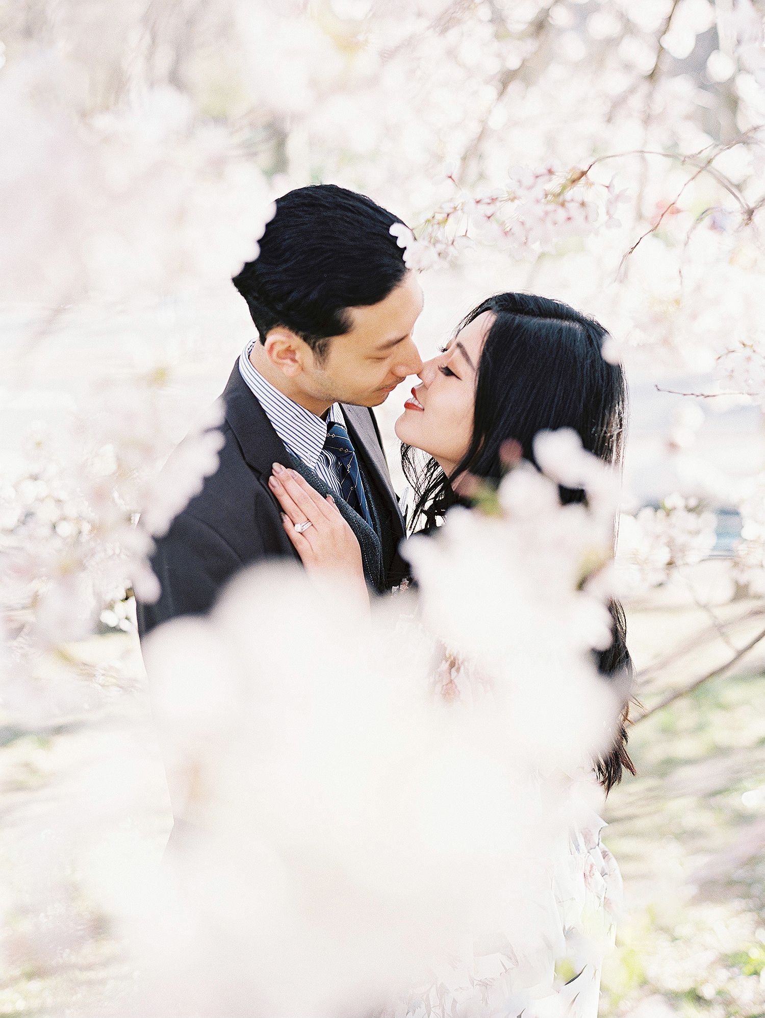 A couple shares tender moments among delicate cherry blossoms in spring.