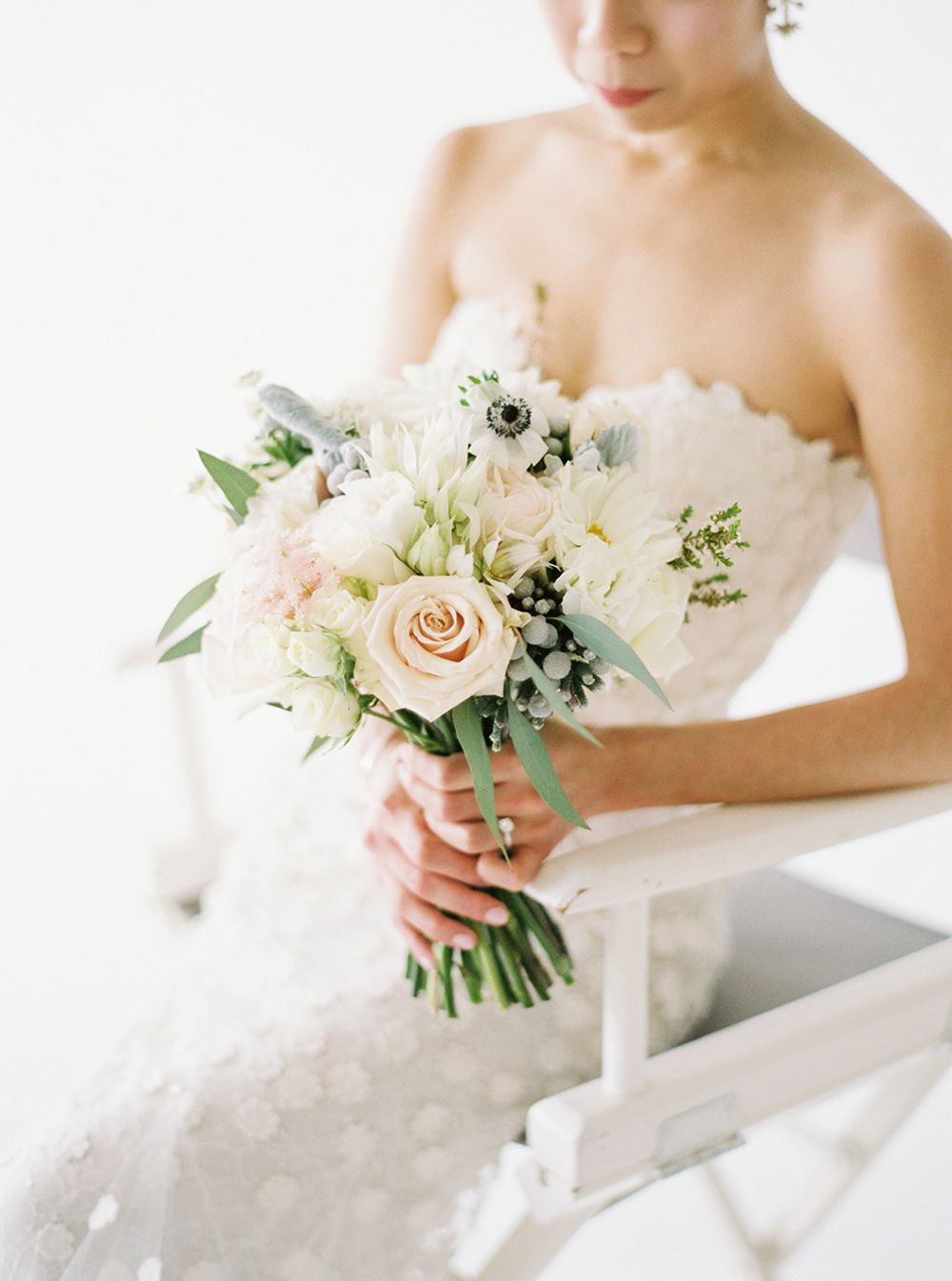 Delicate white and blush bridal bouquet with roses and greenery.