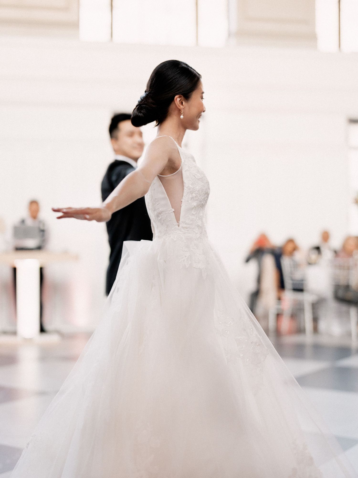 Elegant white wedding dress flowing gracefully during a dance in a bright indoor venue.