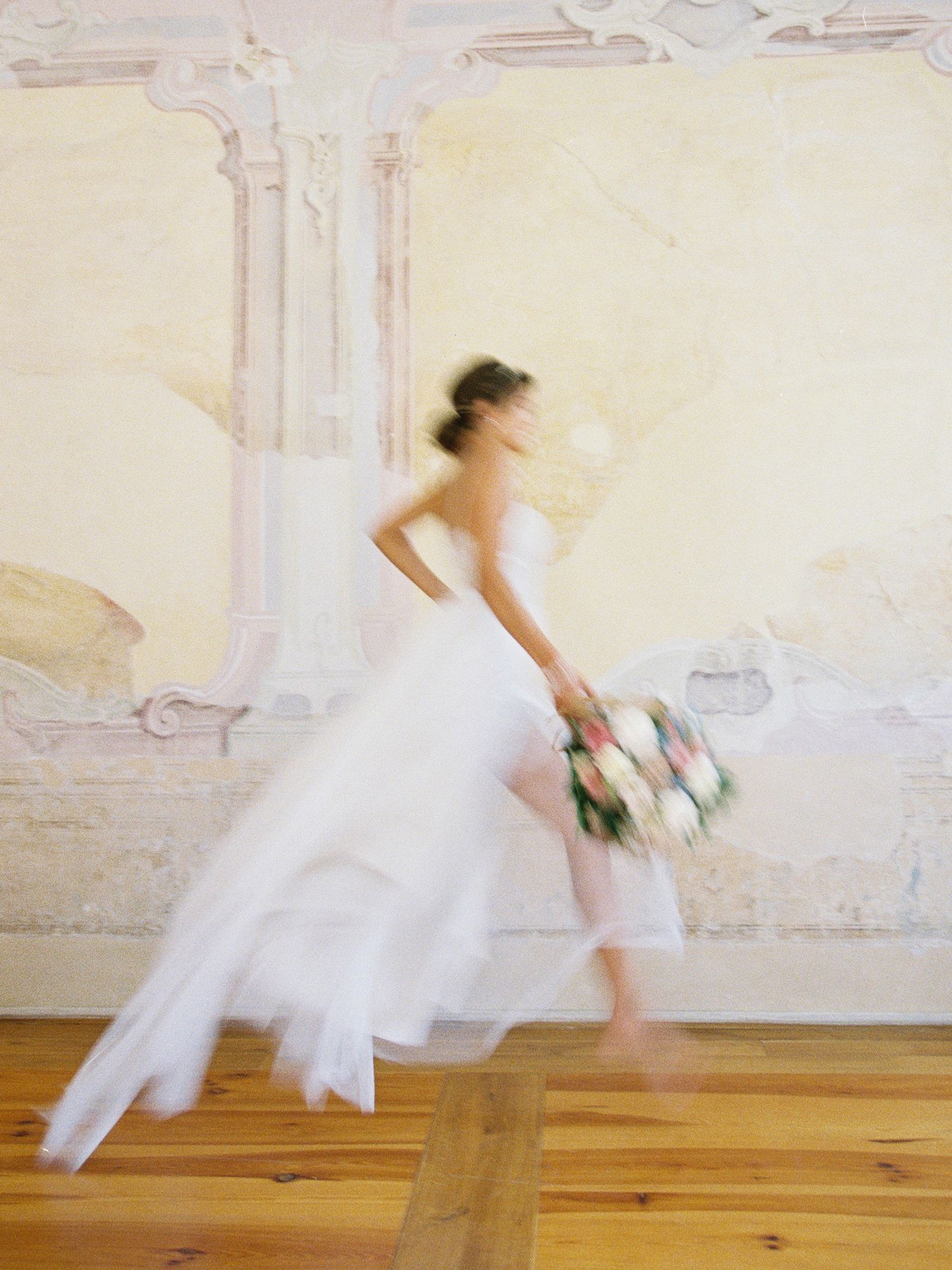Motion blur of white fabric swirling on wooden floor in bright interior.