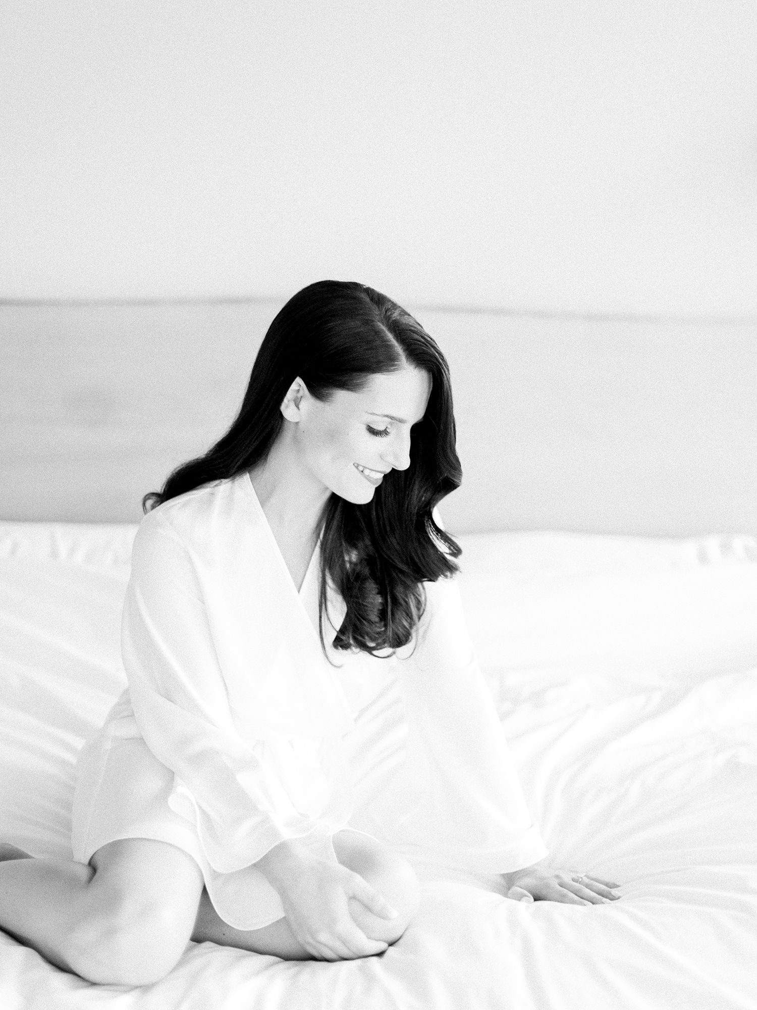 Artistic black and white portrait of person in white shirt on bed.