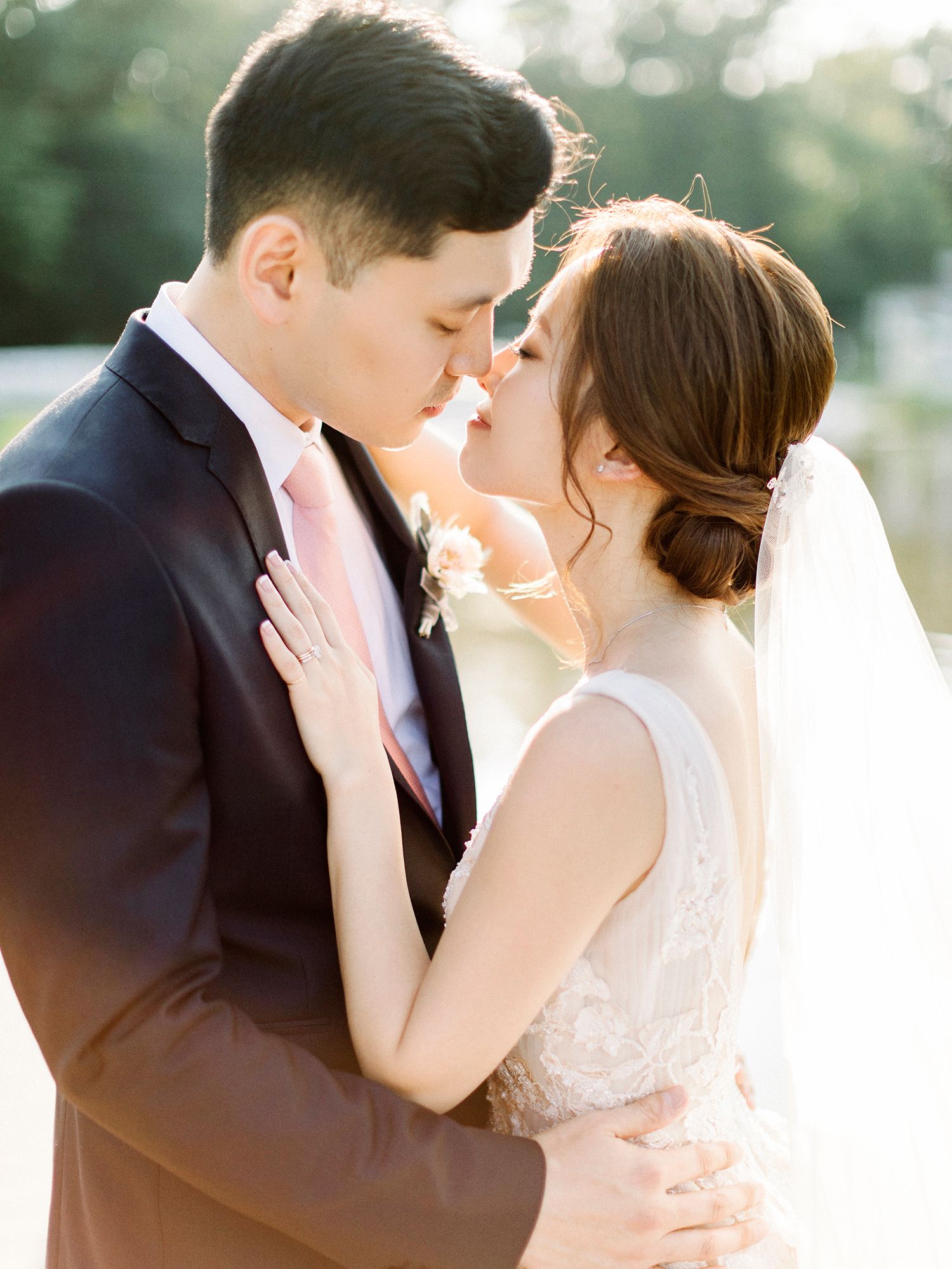 A romantic wedding moment captured in soft sunlit bokeh during an outdoor ceremony.