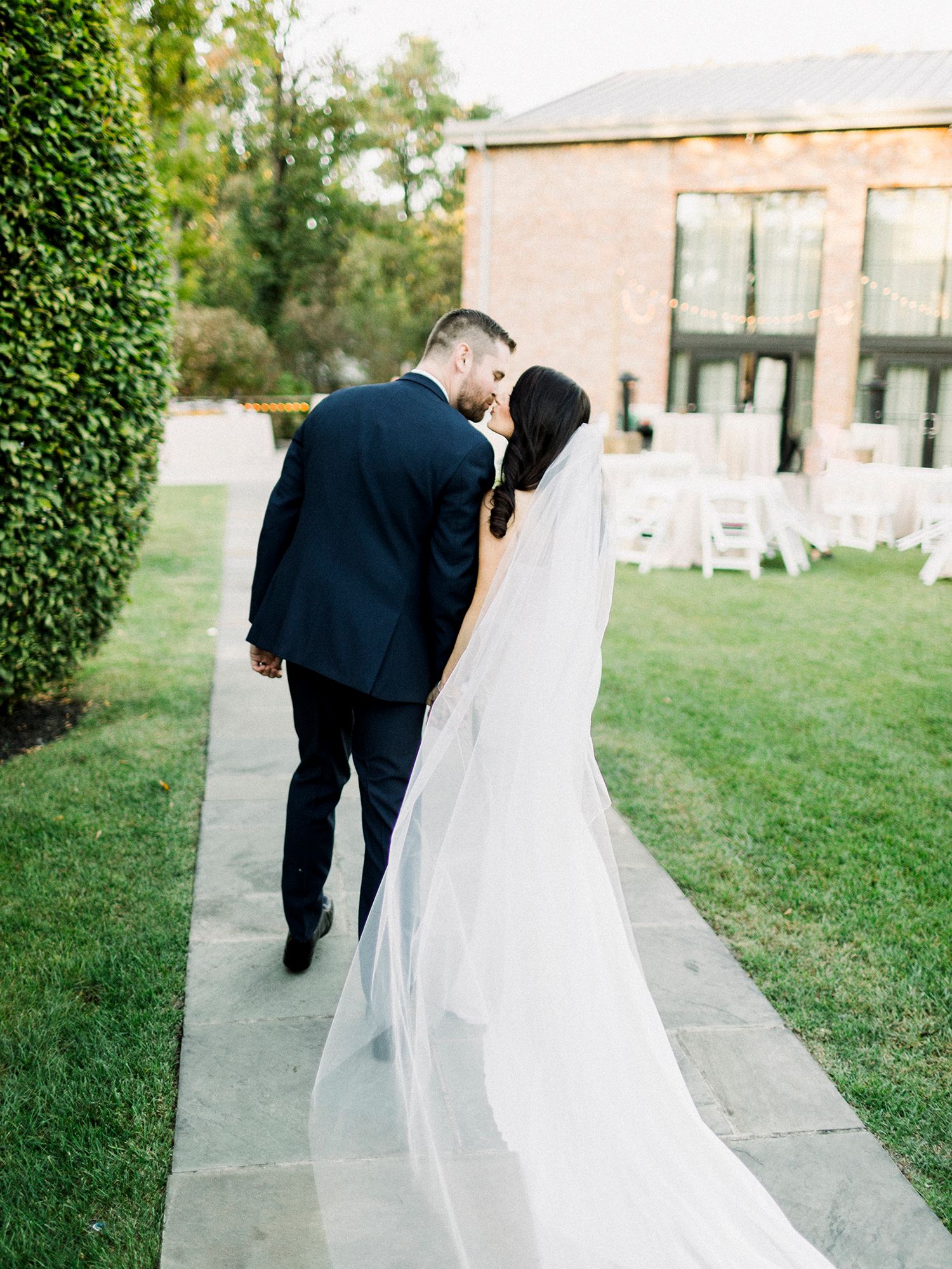Couple walking along a curved pathway surrounded by manicured lawns and garden scenery.