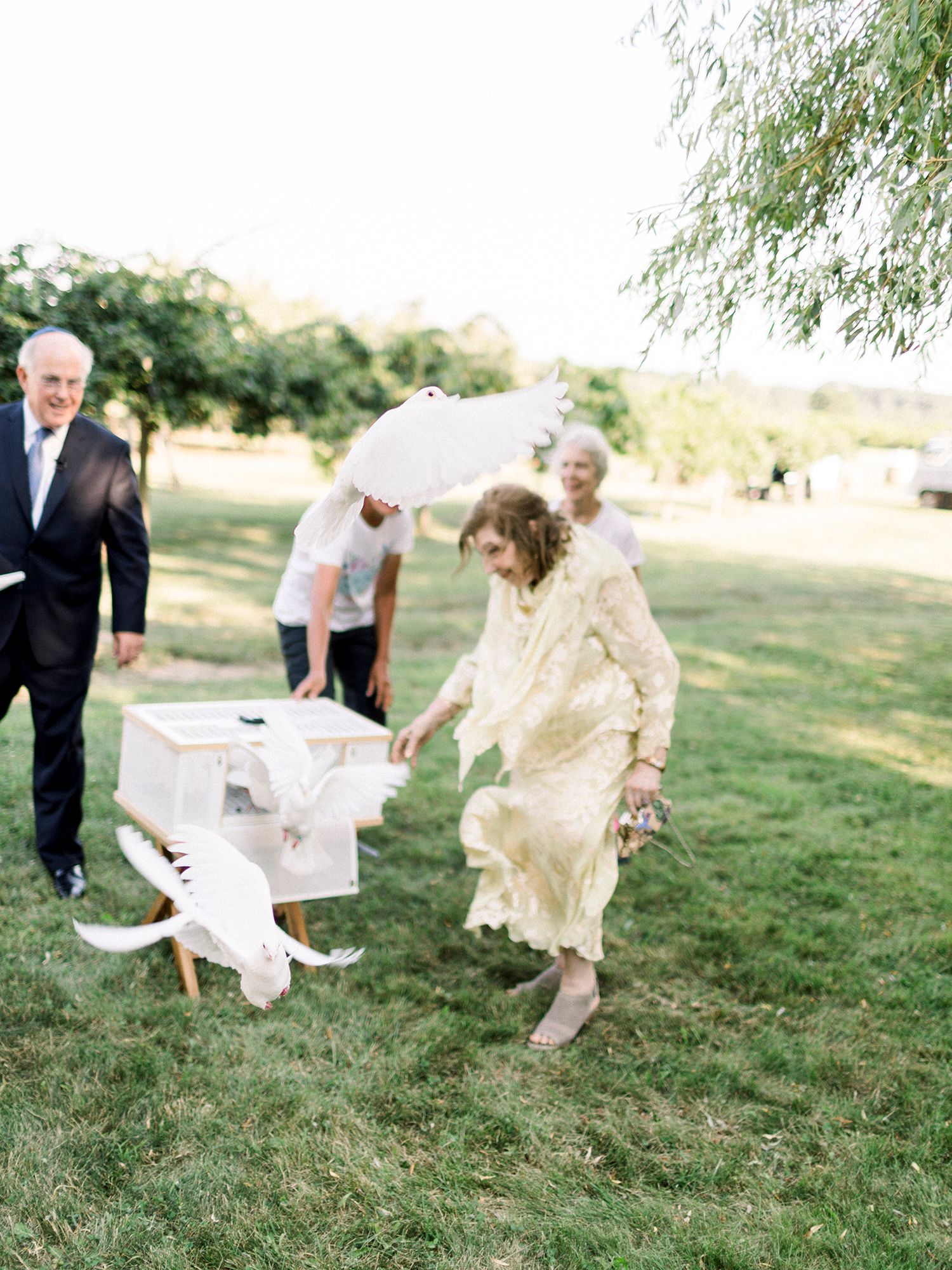 Wedding guests release white doves during outdoor celebration.