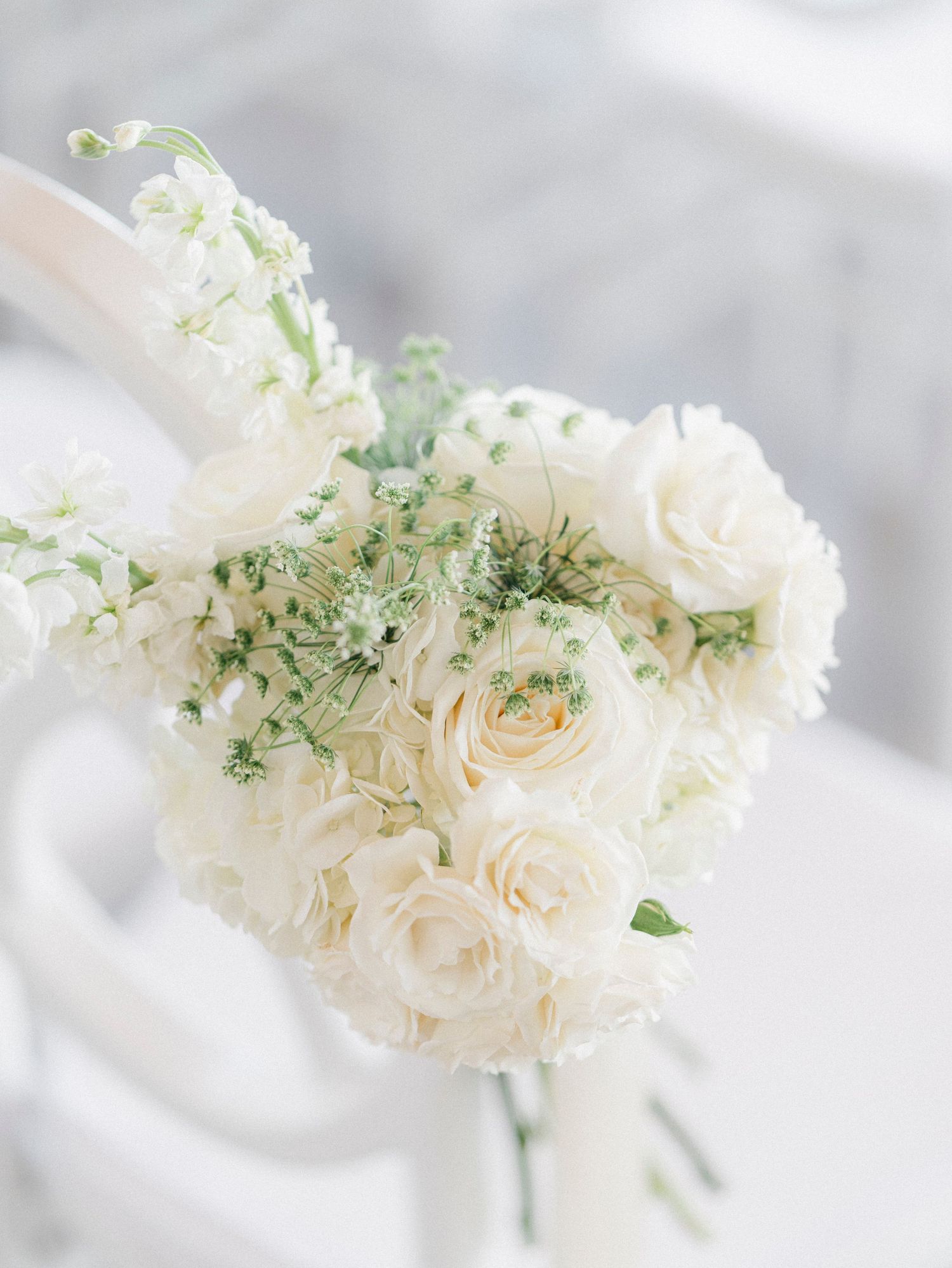 Delicate white roses and greenery arranged in soft, romantic wedding bouquet details.