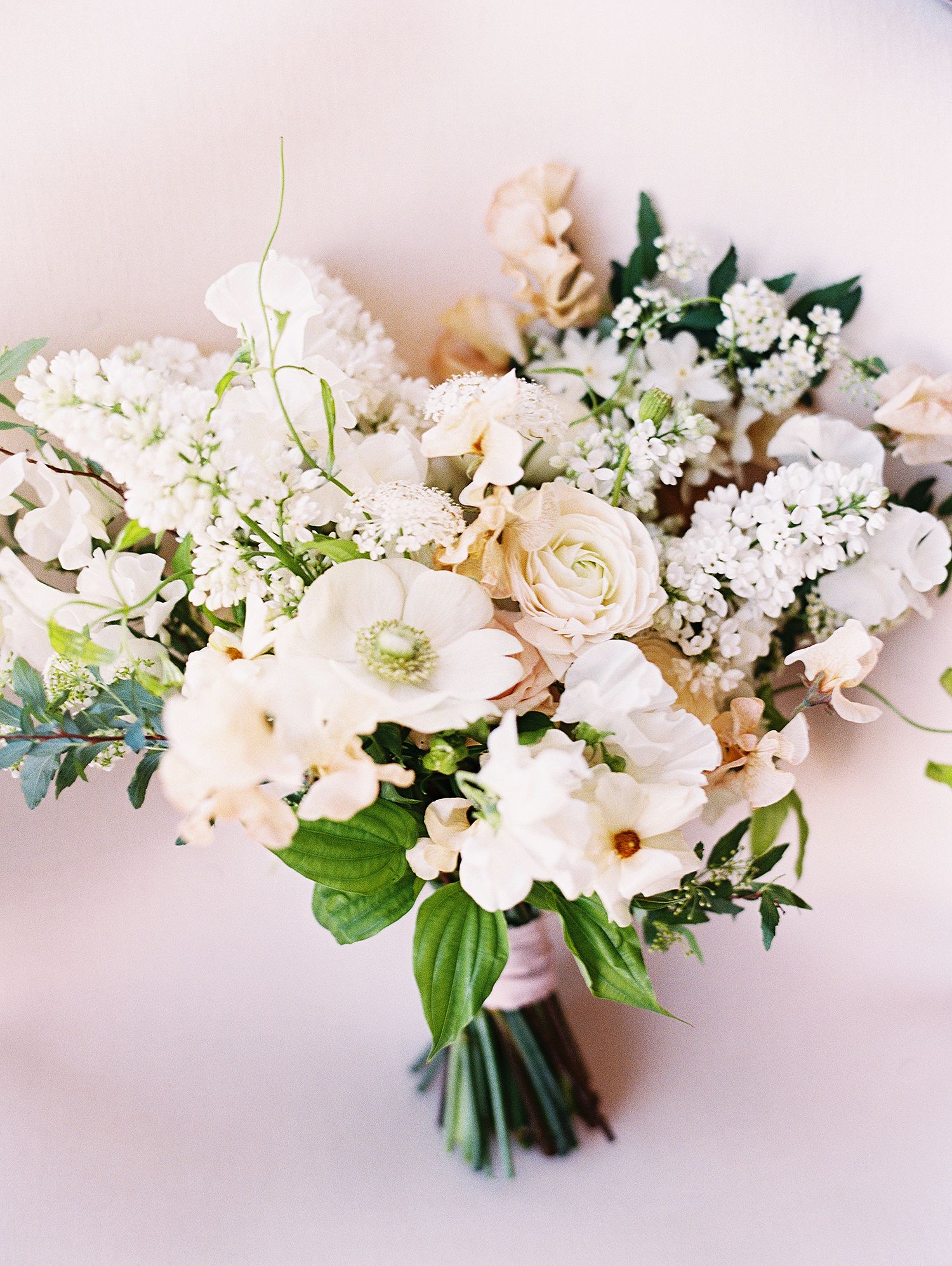 Romantic white and cream floral arrangement with delicate blooms and greenery.