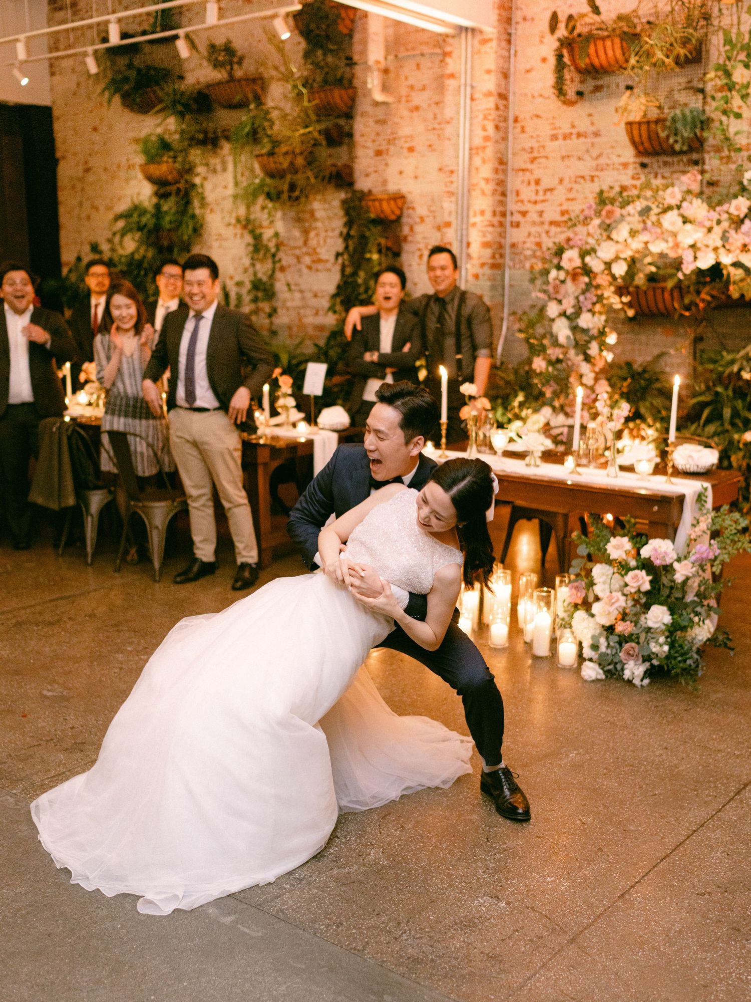 Wedding reception in a rustic brick venue with romantic candlelight and floral decorations.