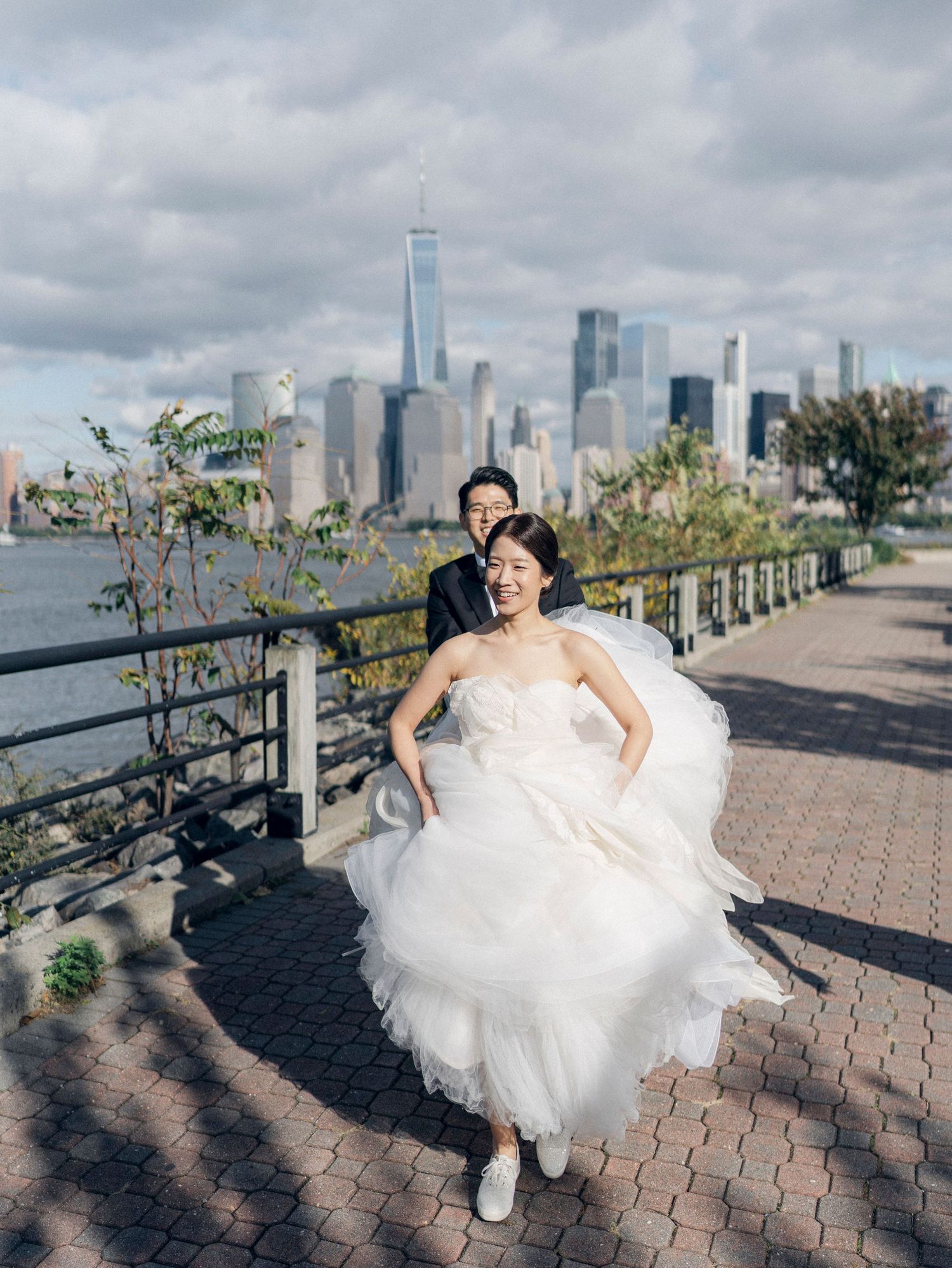 Bride twirls in her white wedding dress against Manhattan skyline backdrop.