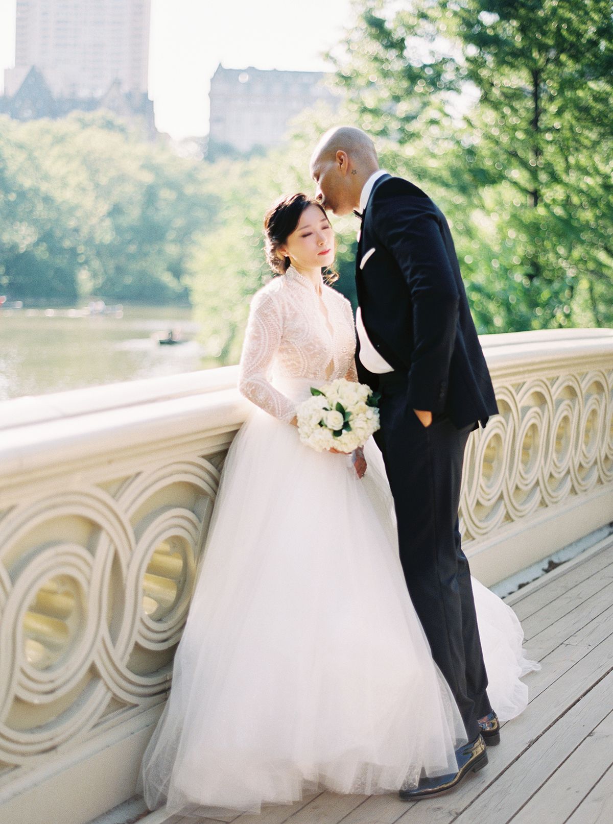 A romantic wedding photoshoot on Bow Bridge in Central Park with the couple sharing intimate moments.