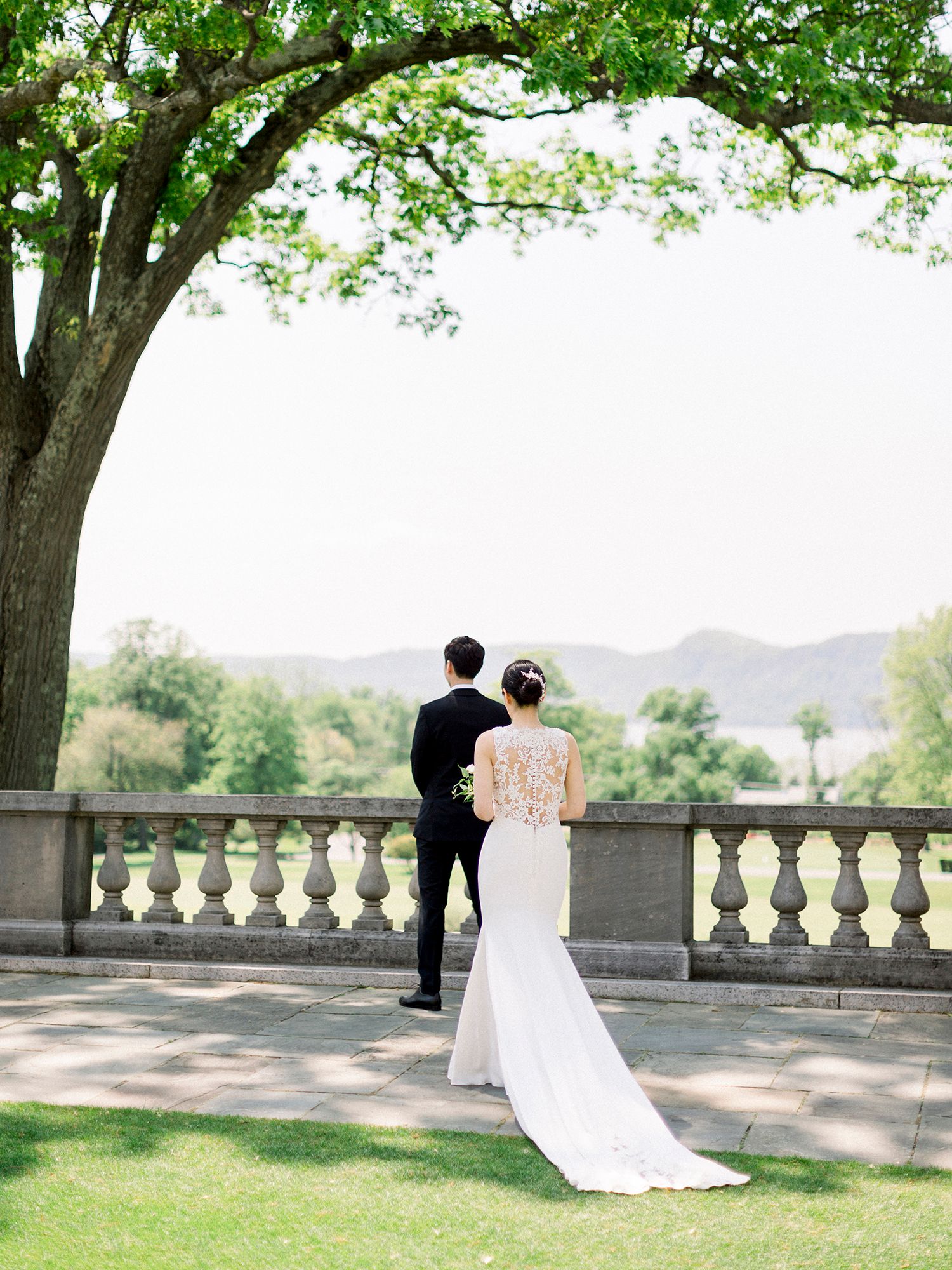 Romantic wedding couple moment on a stone balcony overlooking a scenic landscape.