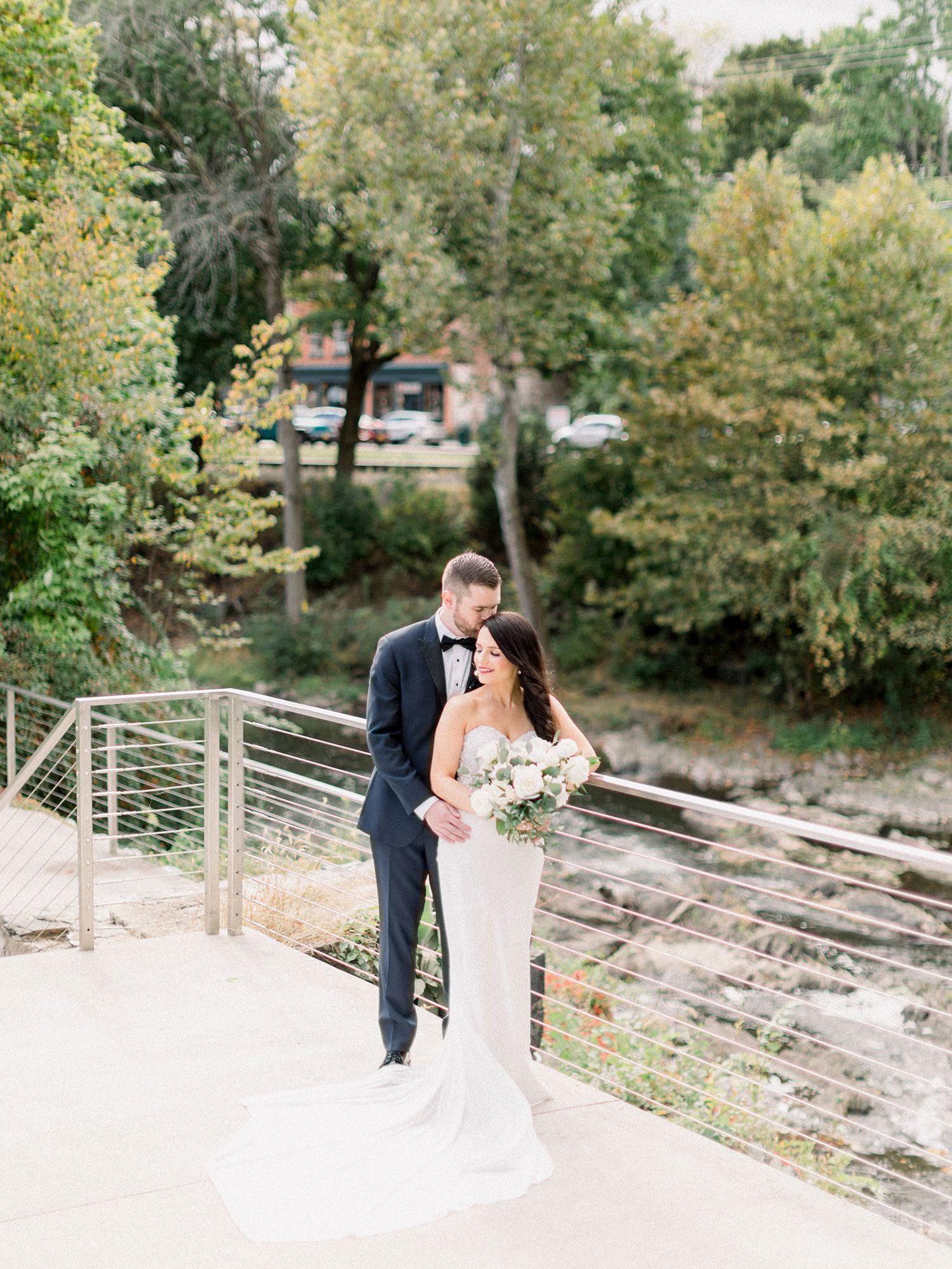 Wedding couple sharing romantic moments on stone pathway surrounded by autumn foliage.