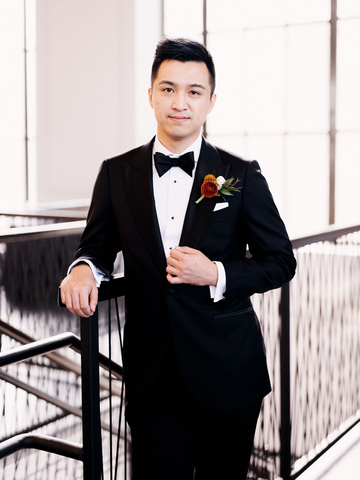 Classic formal portraits in black tuxedo with bow tie against white interior.