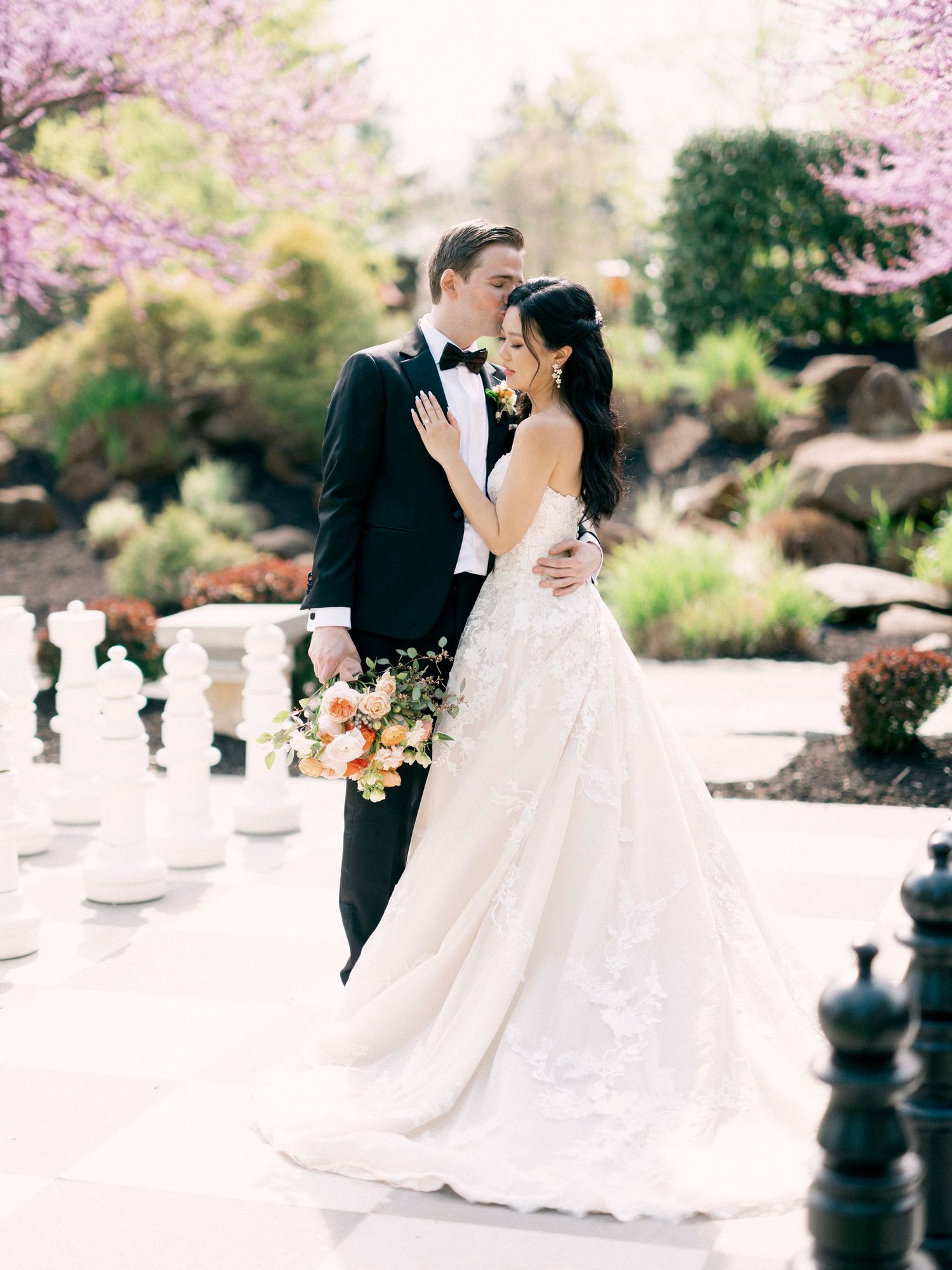 Romantic wedding portraits with giant chess pieces and cherry blossoms in bloom.