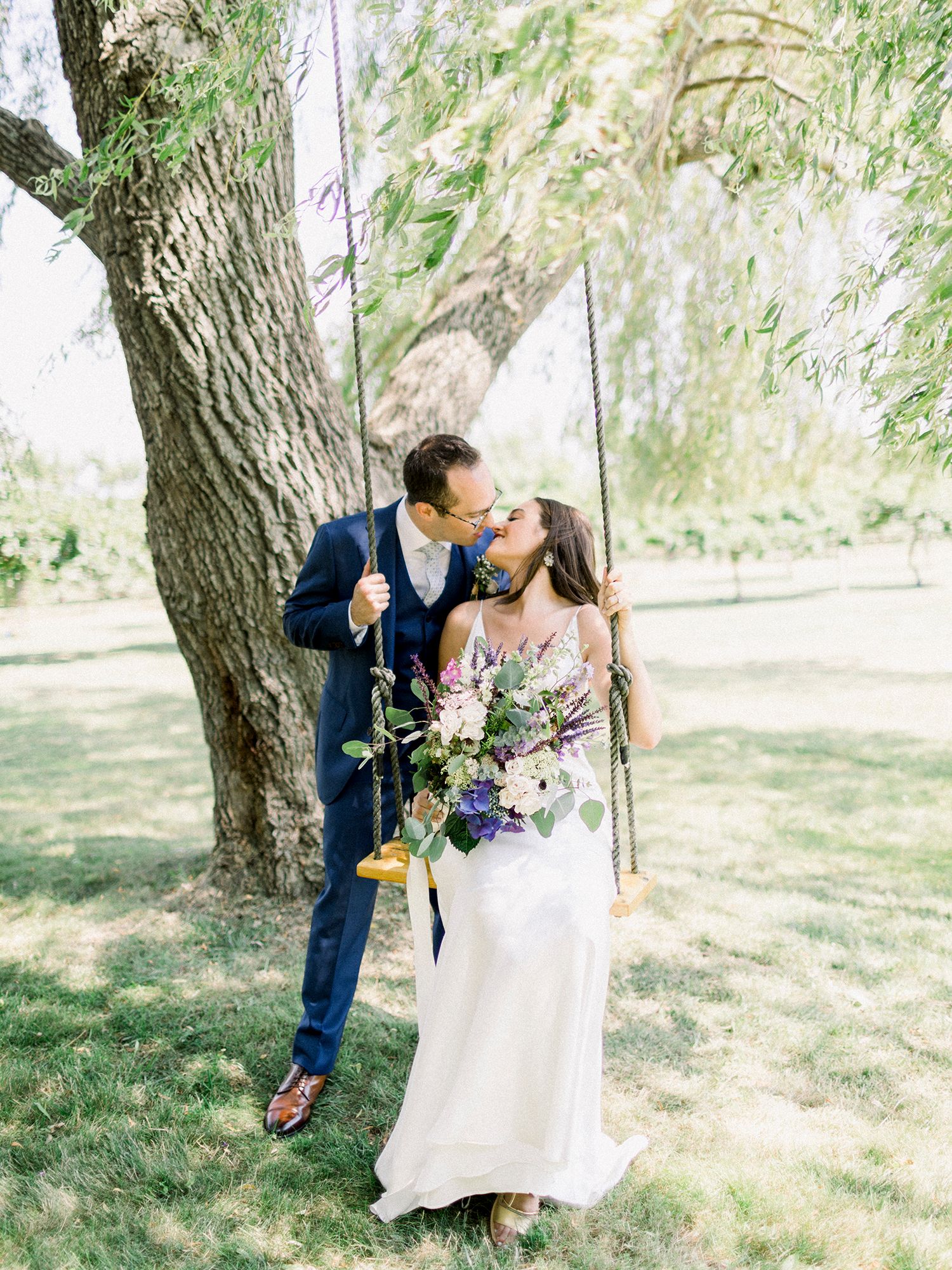 A romantic wedding swing scene with floral decorations in a sunlit garden.