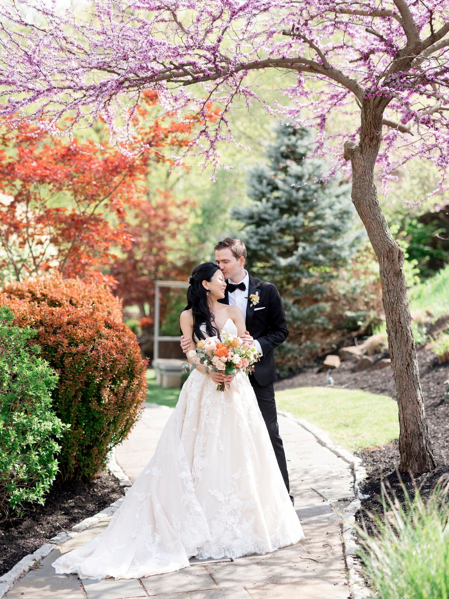 Wedding couple portraits under blooming cherry trees with colorful spring foliage.