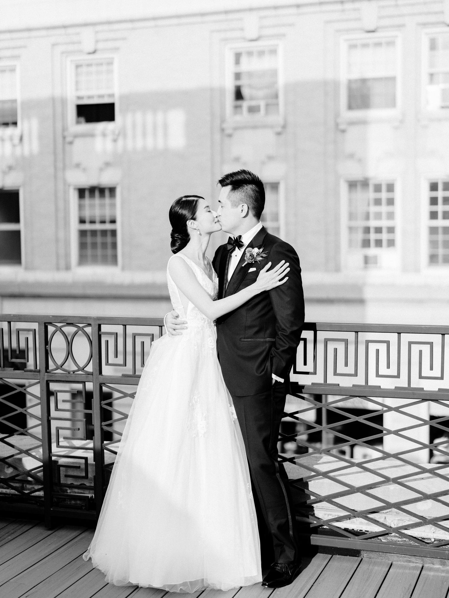 Black and white wedding photography on a vintage wooden deck with geometric railings.