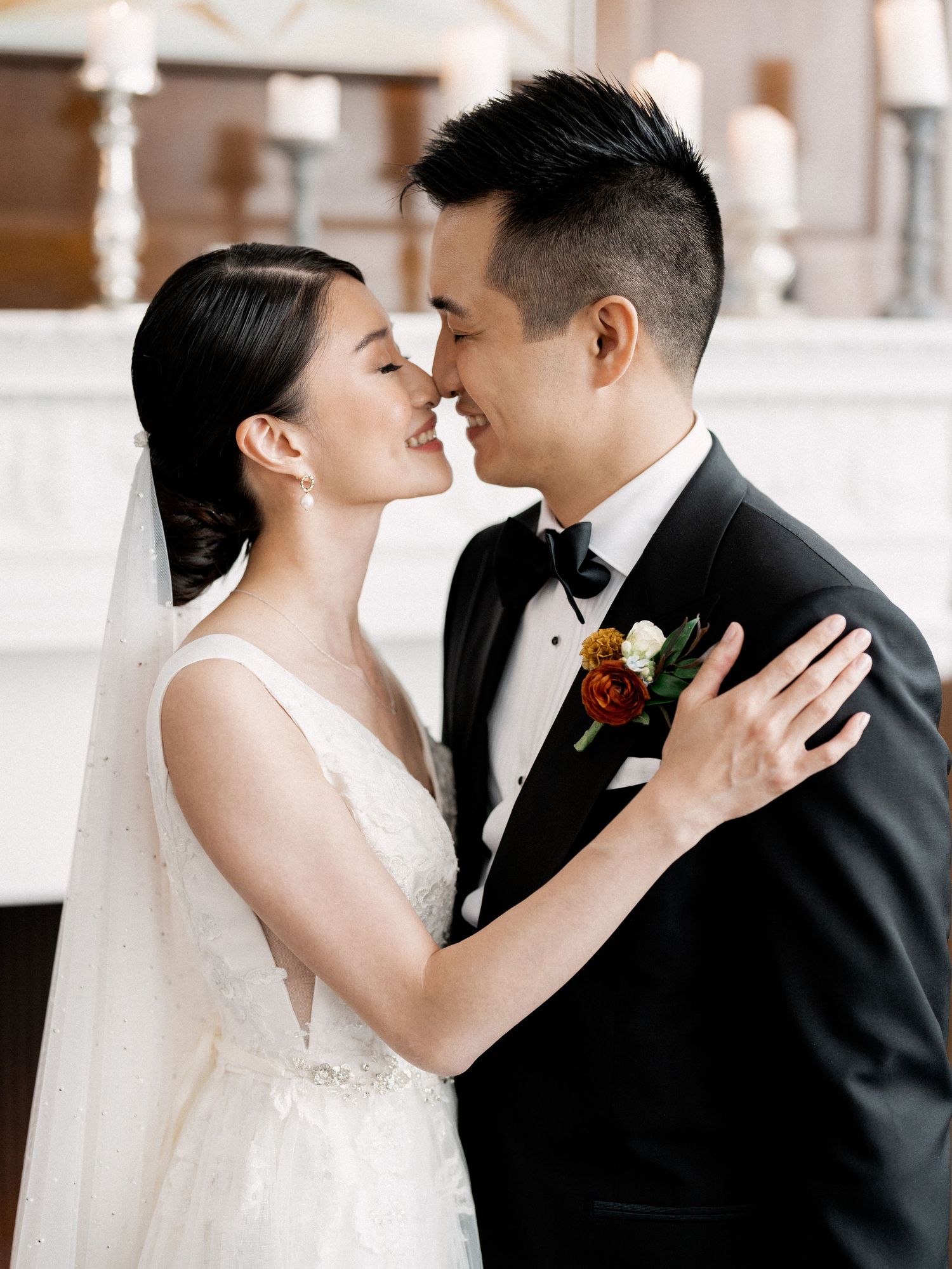 Intimate wedding moment captured in soft natural light with delicate floral details.